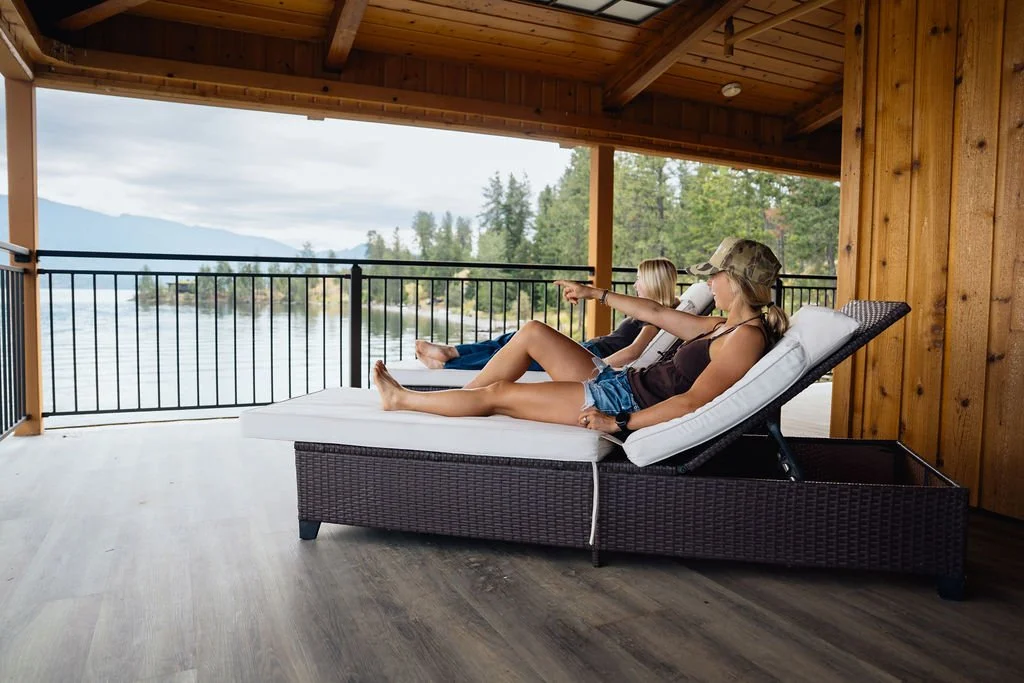 Two guests relaxing on a covered balcony above Lake Pend Oreille in Sagle, Idaho