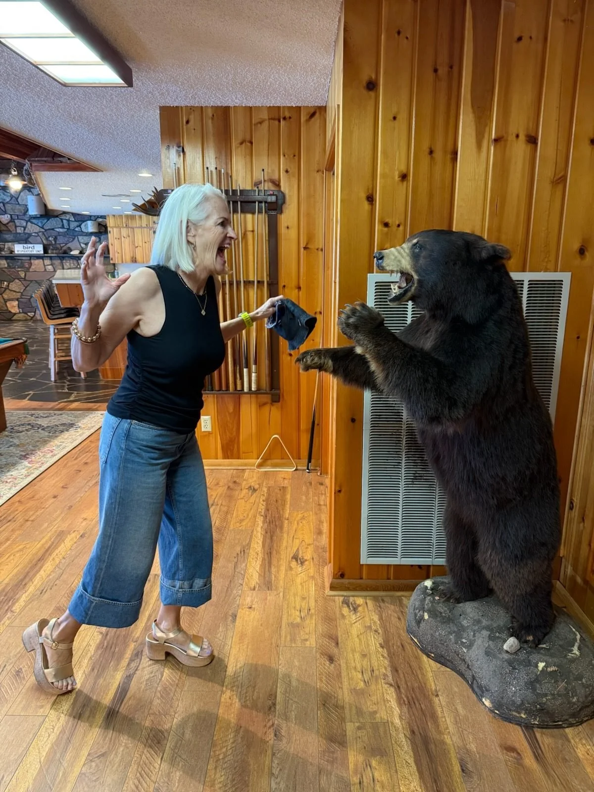 A guest posing with the standing bear mount inside the lodge at The Retreat on Lake Pend Oreille