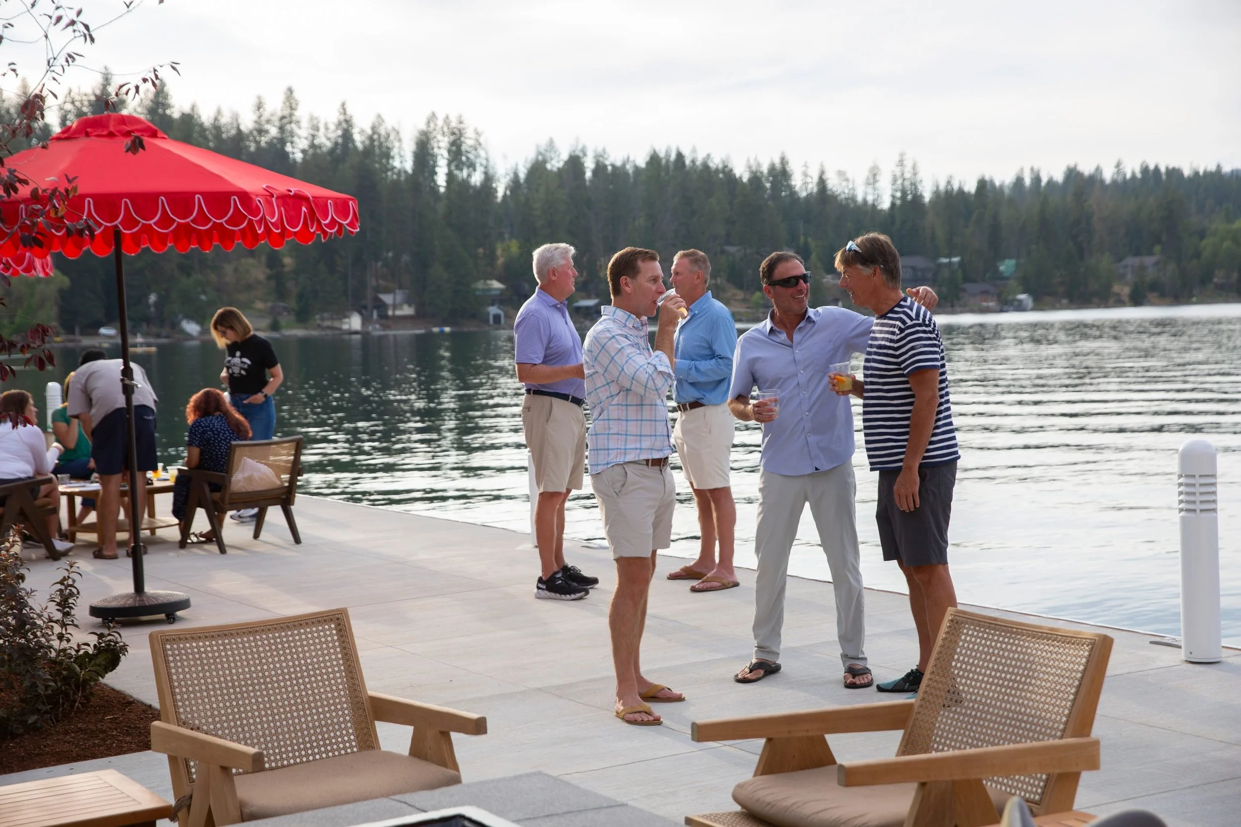 Guests with drinks beside the water at The Retreat on Lake Pend Oreille in Sagle, Idaho
