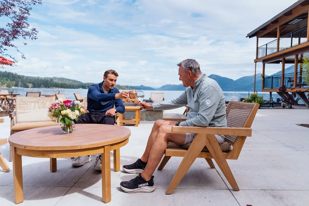 Two guests sharing a drink at a table overlooking Lake Pend Oreille in Sagle, Idaho