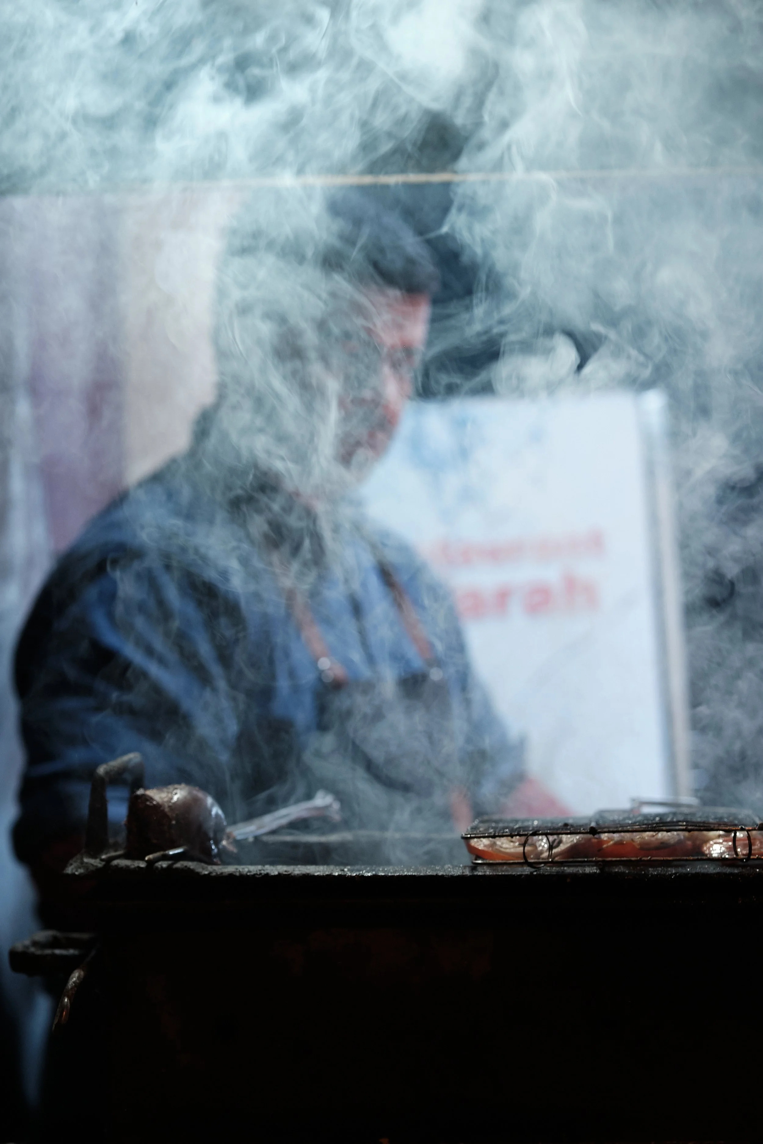 Immagine di una persona che cucina o lavora in cucina, vista da dietro attraverso una finestra sporca o appannata.