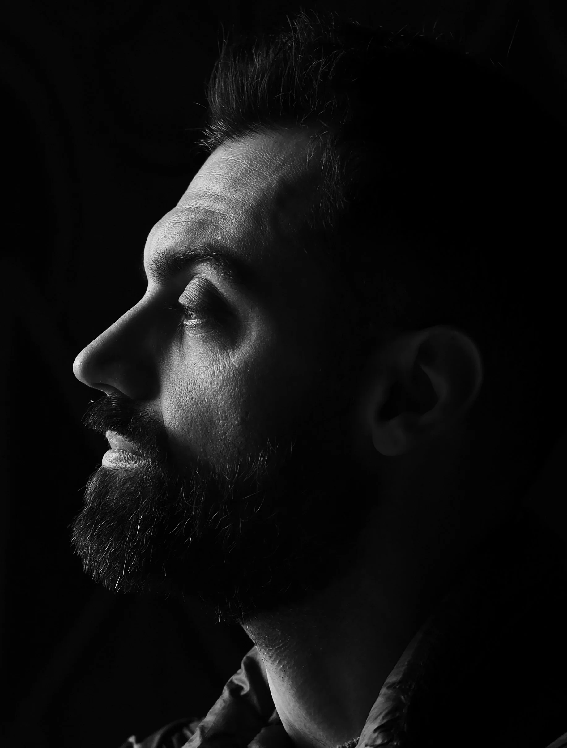 Ritratto in bianco e nero di un uomo con barba e capelli corti, visto di profilo con espressione serena e occhi chiusi.