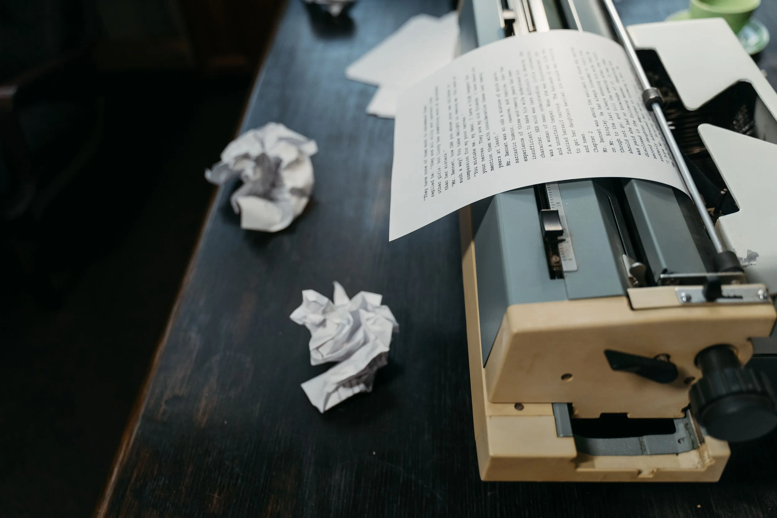 A printer on a desk printing a document with crumpled paper scattered around.