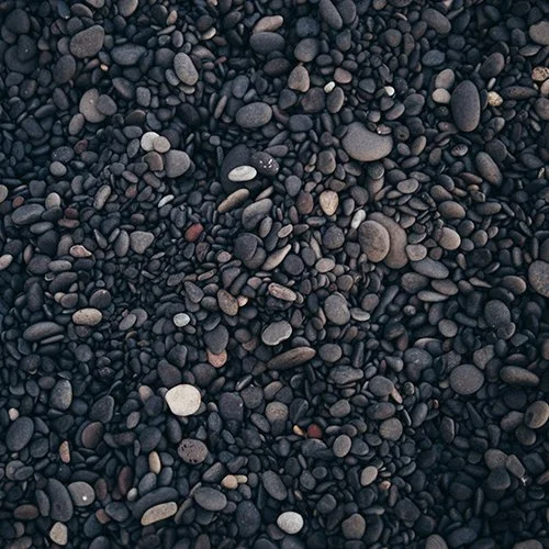 Close-up of black pebbles and small stones on a beach or surface.
