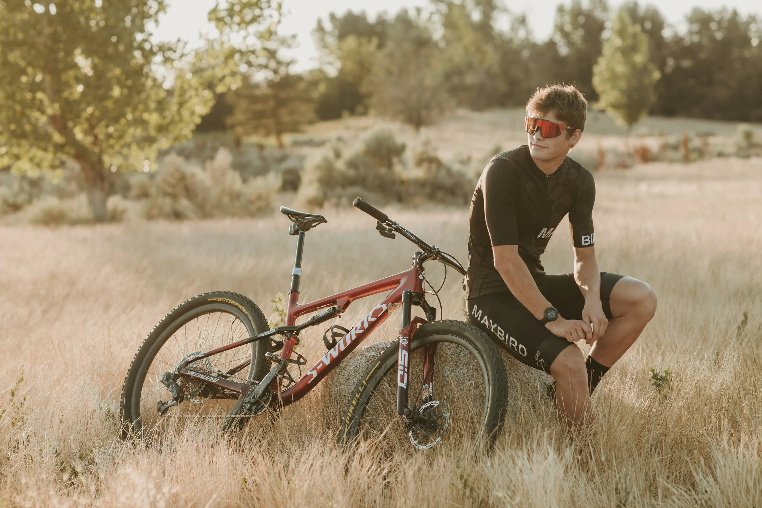 Mountain Biker Senior Boy sitting on rock with bike in the golden field.
