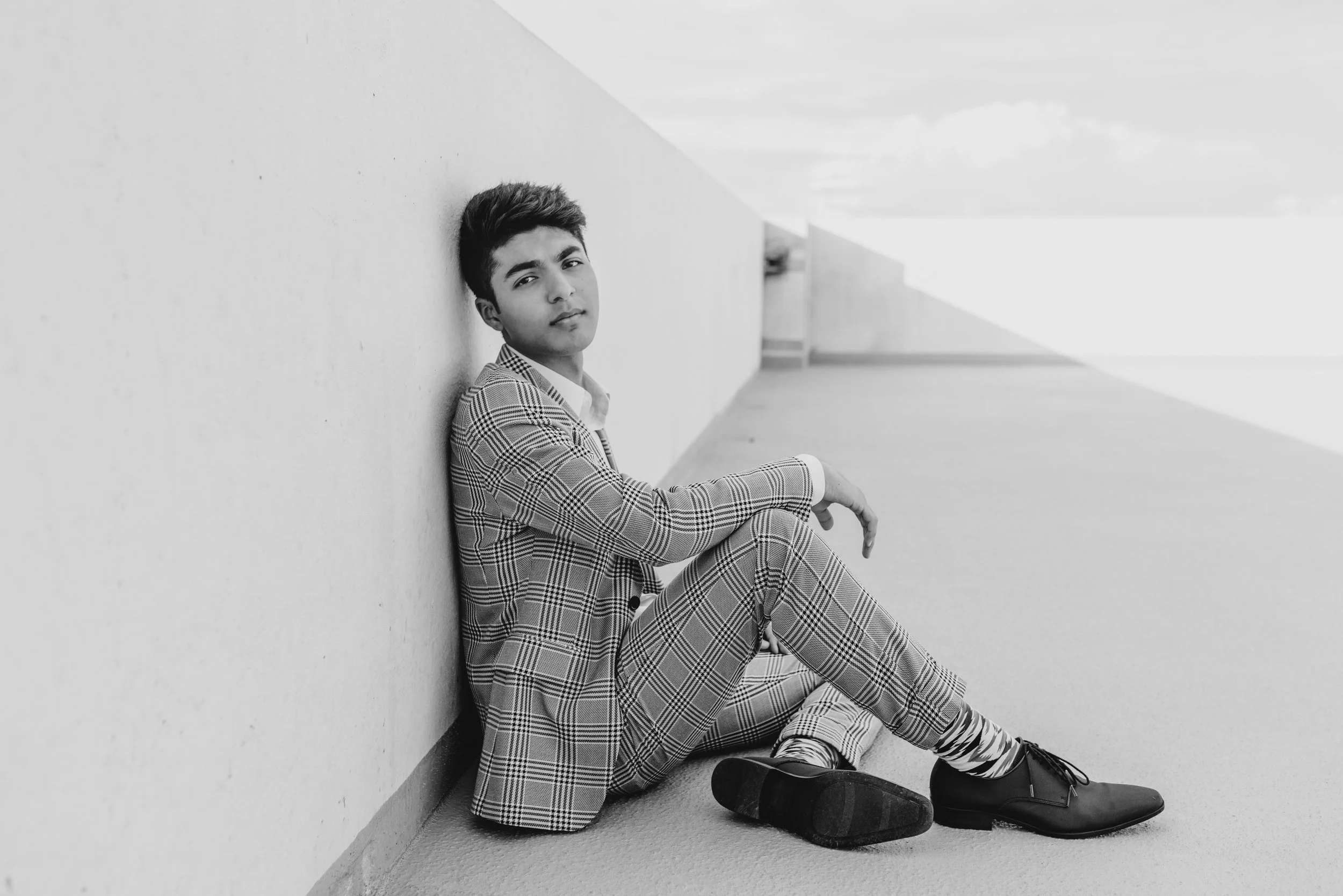 Senior boy in suit sitting in parking garage
