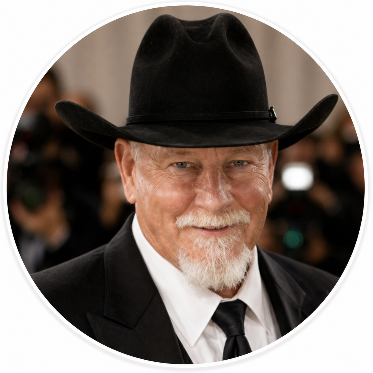 An older man with a white beard and mustache wearing a black cowboy hat, black suit, white shirt, and black tie at a formal event.