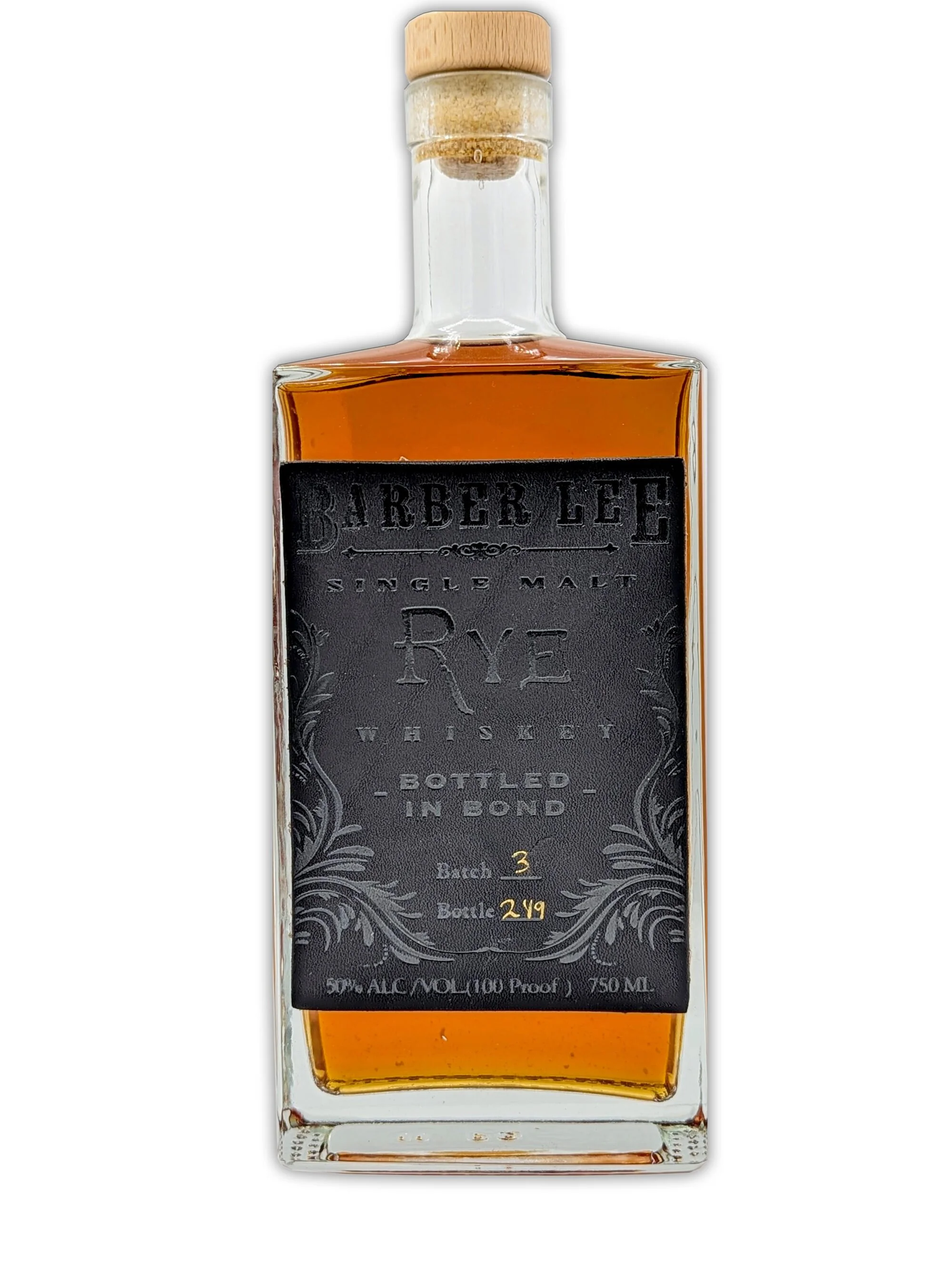 A glass bottle of amber-colored whiskey with a black label and gold lettering, and a wooden cork on top.