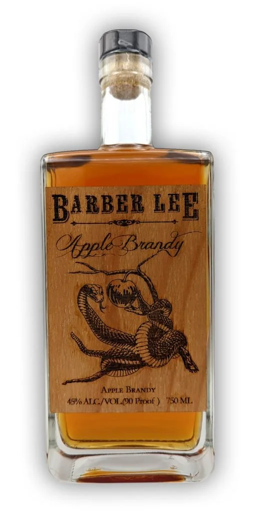 A bottle of Barber Lee Apple Brandy with a light brown label featuring a snake wrapped around an apple. The bottle contains amber-colored liquid and has a clear glass with a black cap.