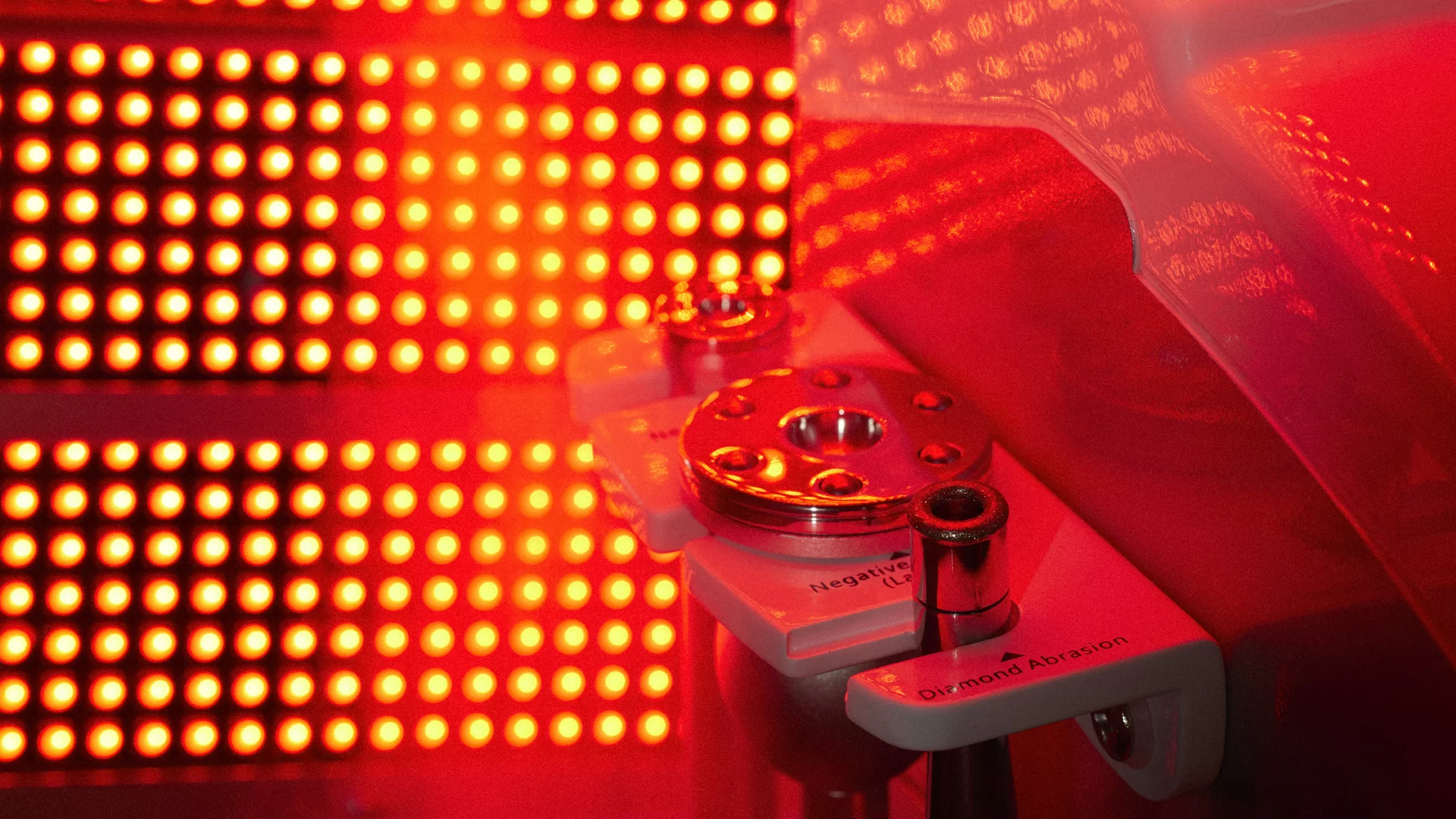 Close-up of a red LED display panel and a laser device with metallic components, a label that reads 'Negative' and a white device labeled 'Diamond Abrasion'.