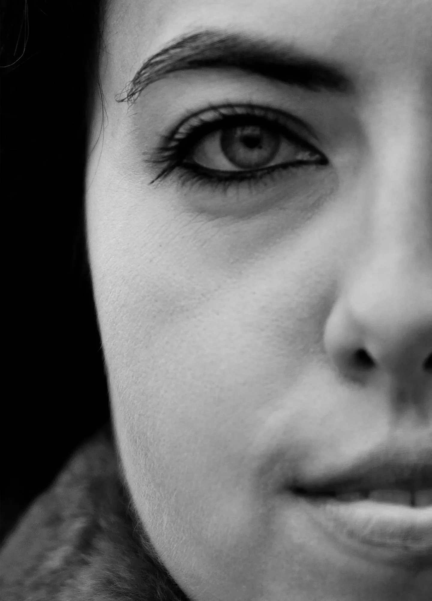 Close-up black and white photo of a person's eye, eyebrow, and part of their nose.