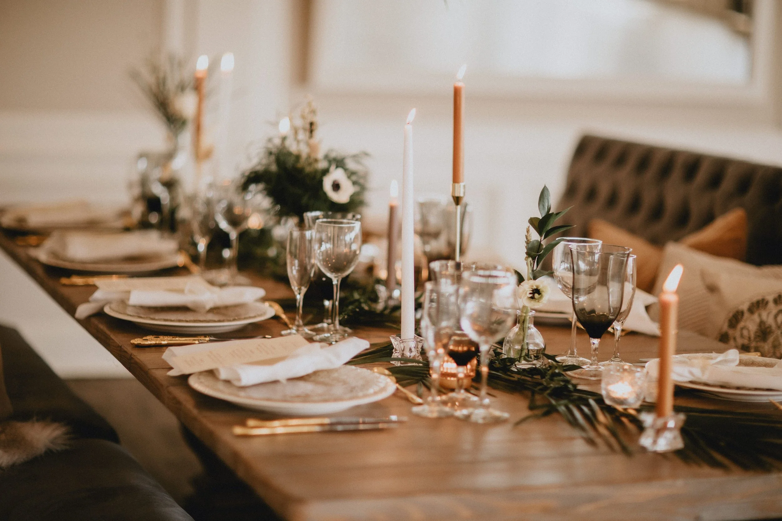 A close-up of a decorated dining table with candles, glassware, and floral arrangements for a special occasion.