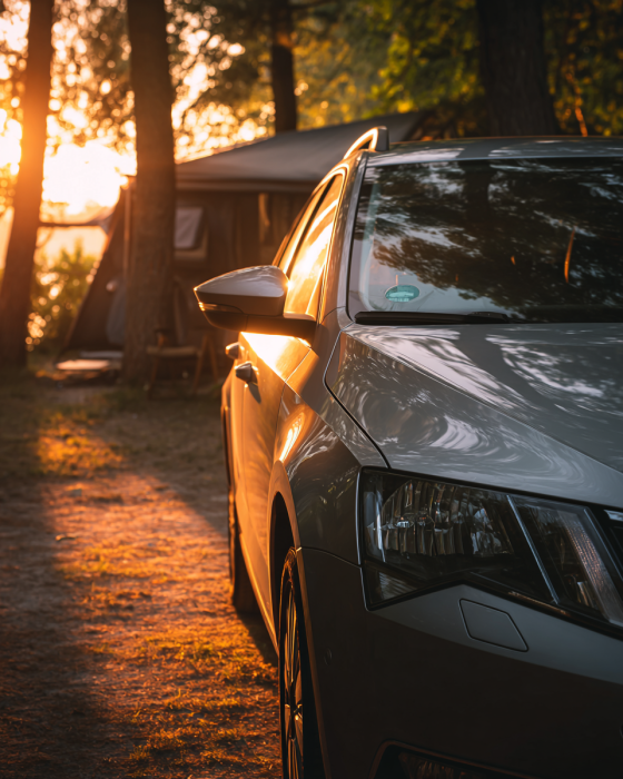 Family estate car parked at a European campsite during sunset with camping accommodation in the background.