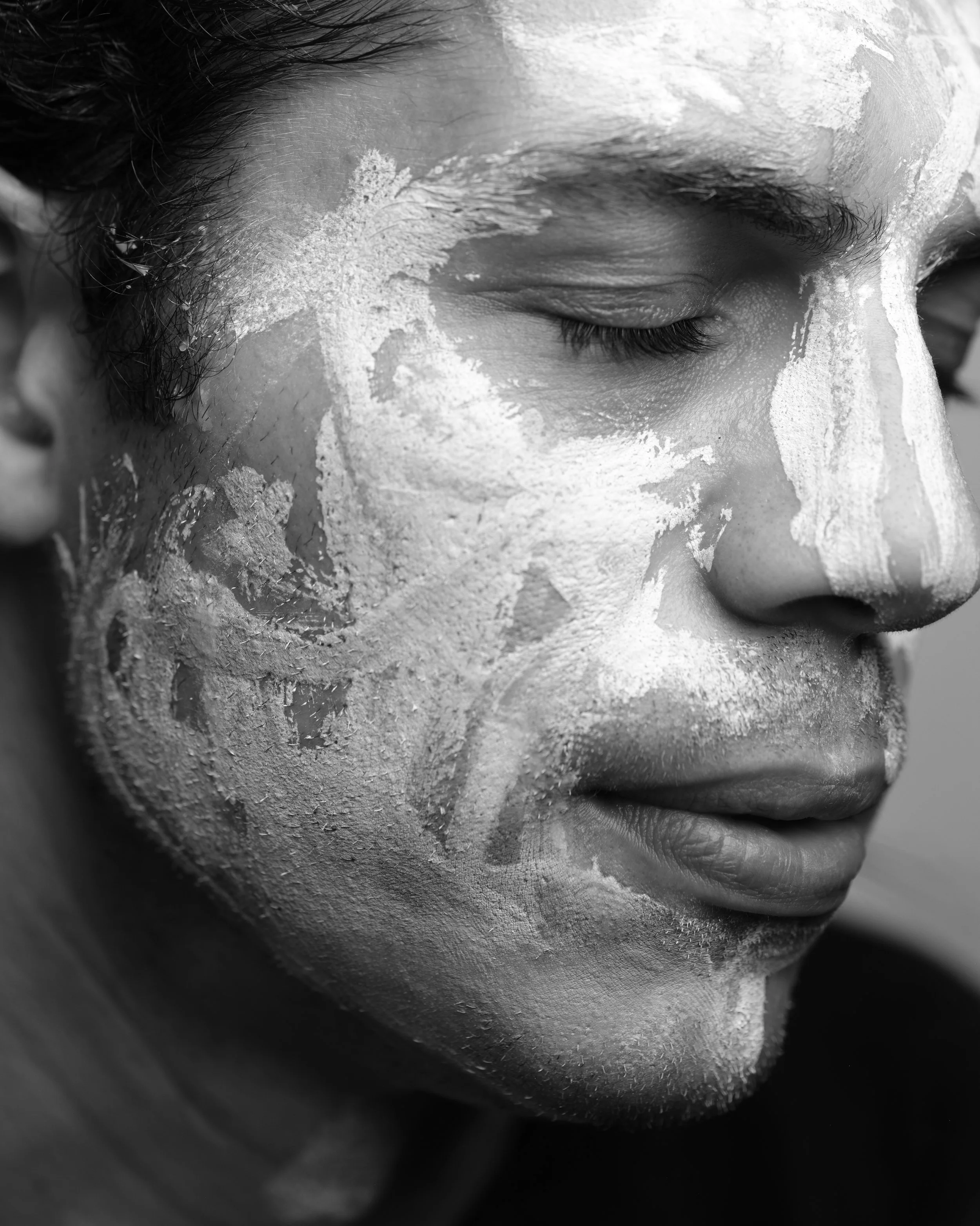 Close-up of a person's face with eyes closed and soap and water on their face.