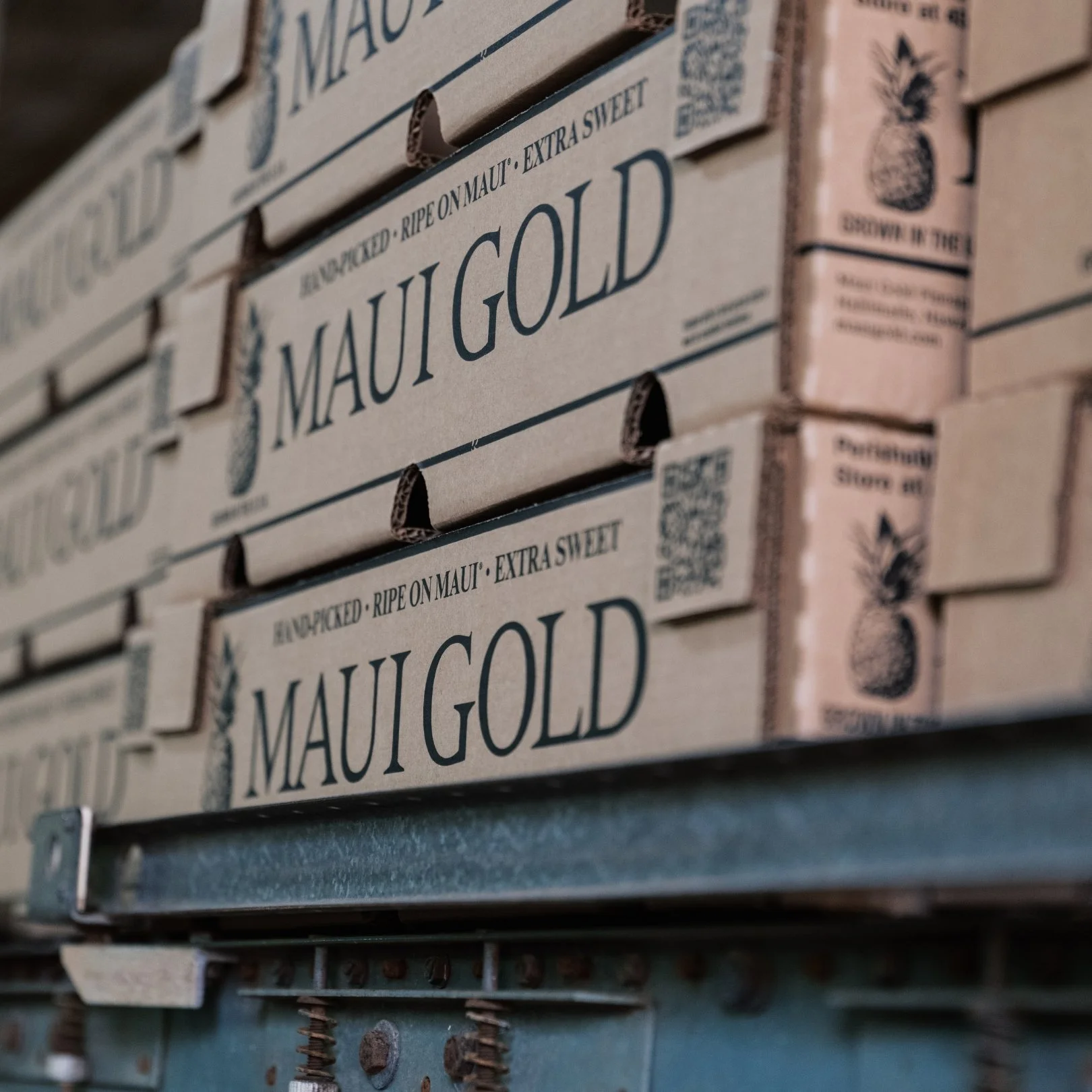 Close-up of stacked boxes of MauiGold pineapple, with brand name and product description on the front.