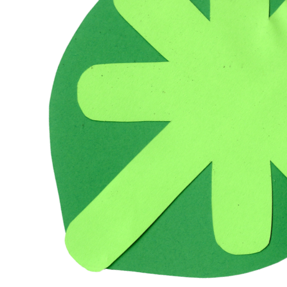 Close-up of a green paper cutout shaped like a clover on a darker green background.