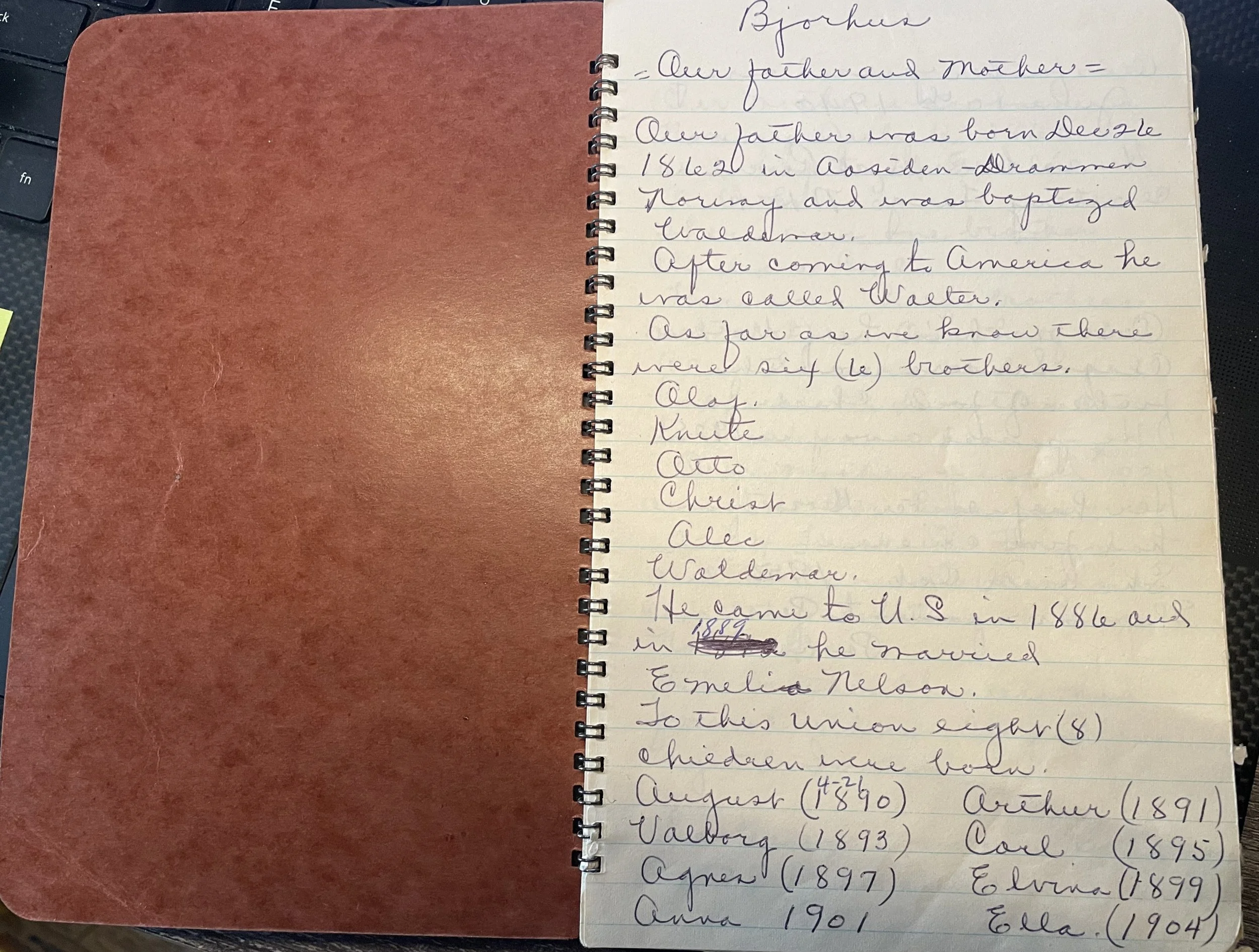 A notebook with handwritten text about someone's ancestors, listing names and birth years.