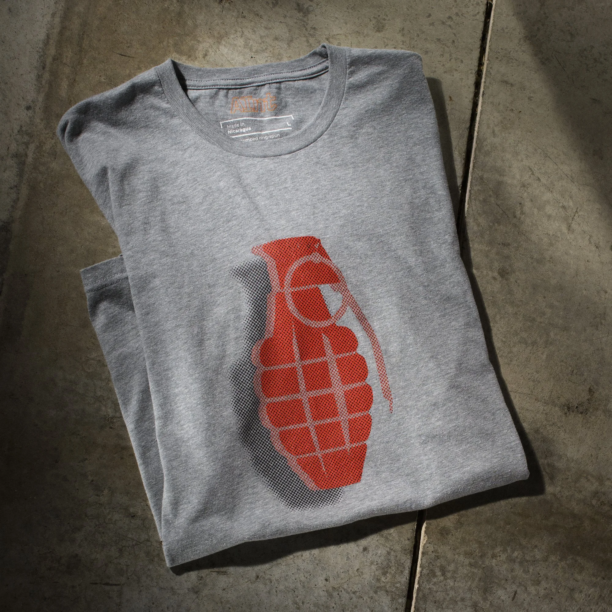 AInt-grenade-t-shirt-folded-on-studio-concrete-floor-next-level-6210-dark-heather-gray-with-red-halftone-graphic-of-grenade.jpg
