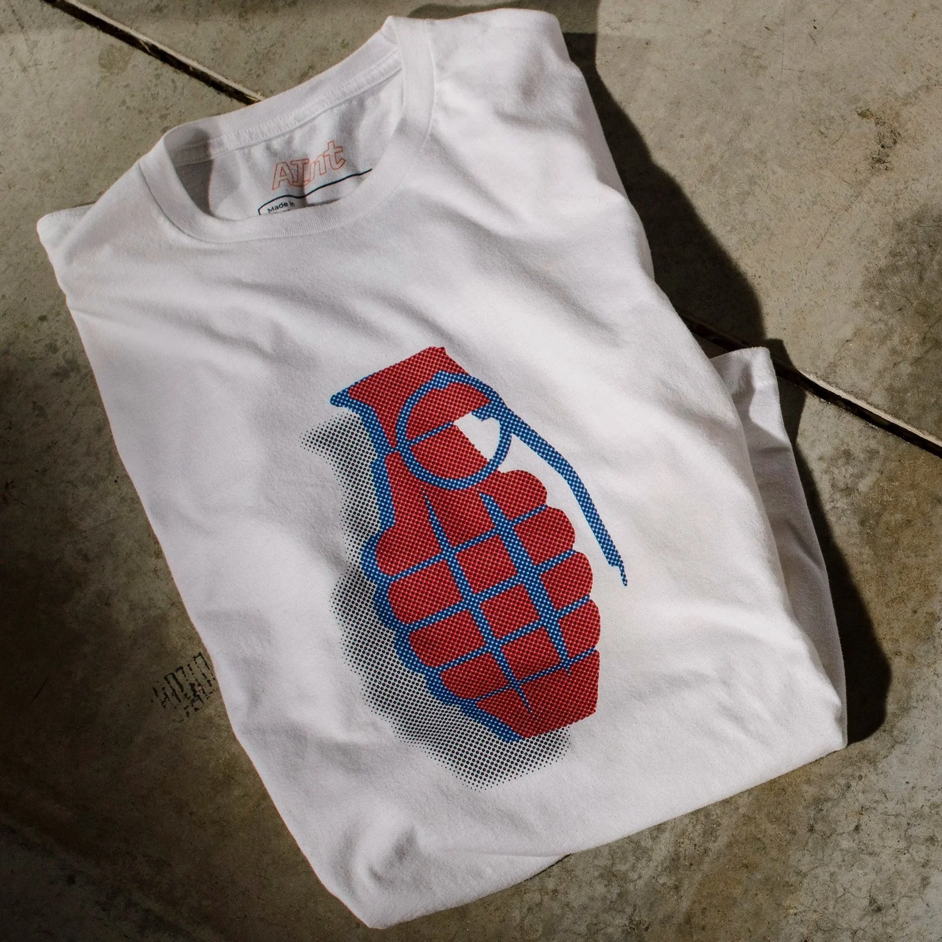 AInt-grenade-t-shirt-white-next-level-6210-red-blue-halftone-grenade-with-black-drop-shadow-folded-studio-concrete-floor.jpg