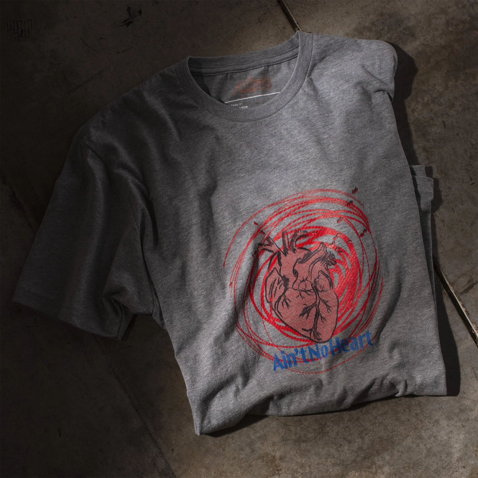 AInt-n0-heart-t-shirt-folded-product-photography-on-studio-concrete-floor-dramatic-light-next-level-6210.jpg