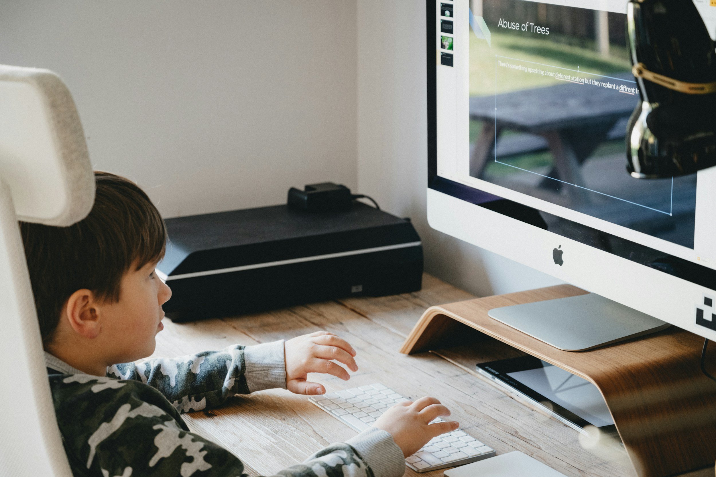 Young child participating in an online speech therapy session using a computer and tablet, developing communication and learning skills through teletherapy