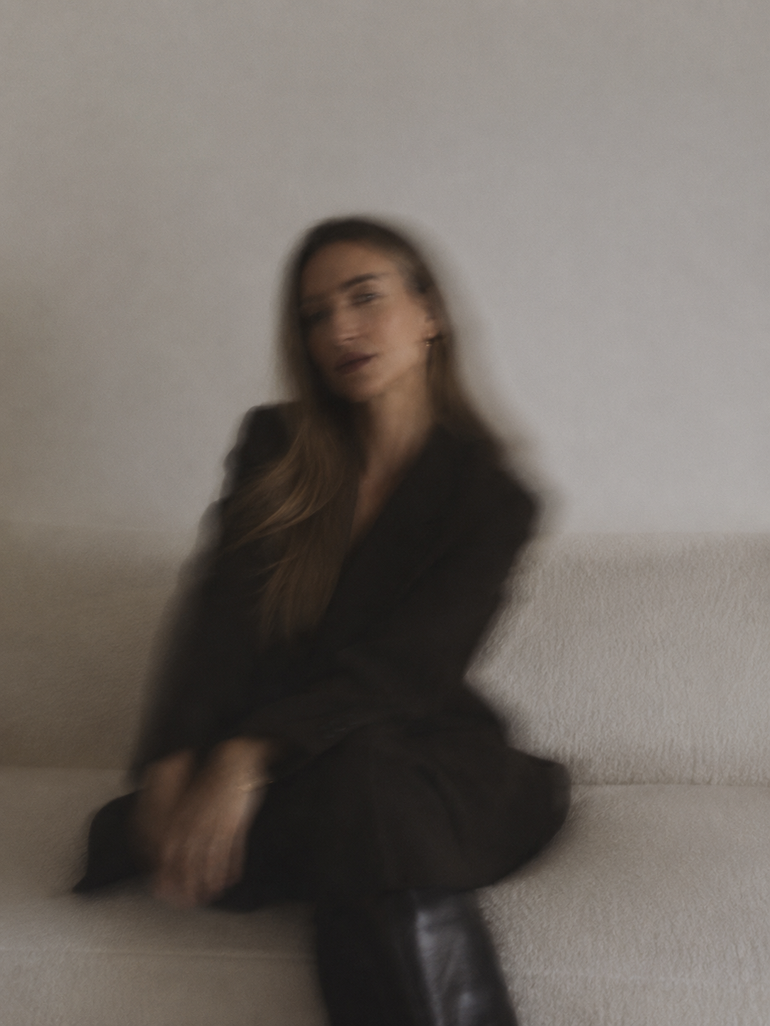brenna akkerman sitting casually on a sofa, blurred image.