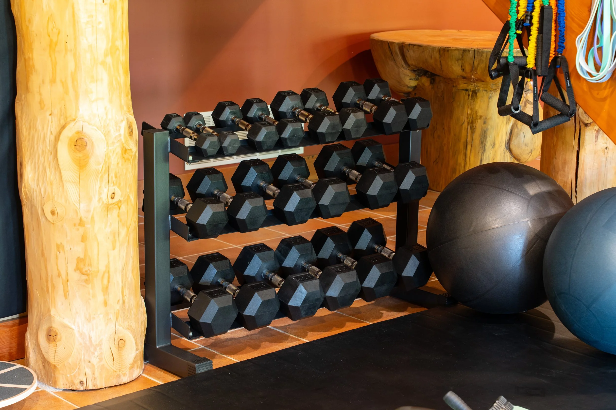 Various black and yellow dumbbells and weight plates on a light-colored surface.