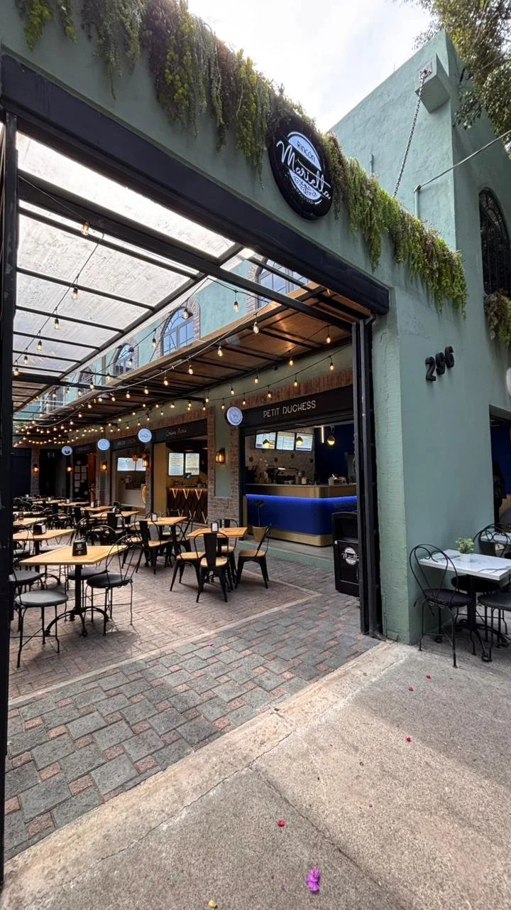 Exterior de un restaurante con mesas y sillas enfrente, con una estructura de toldo corredizo