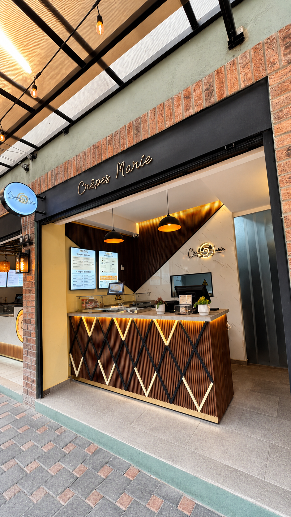 Vista frontal del local llamado "Crêpes Marie"  con una barra de madera decorada con rayas negras y beige, y un fondo de paredes en tonos blancos y beige, con pantallas digitales y plantas decorativas en la mesa.