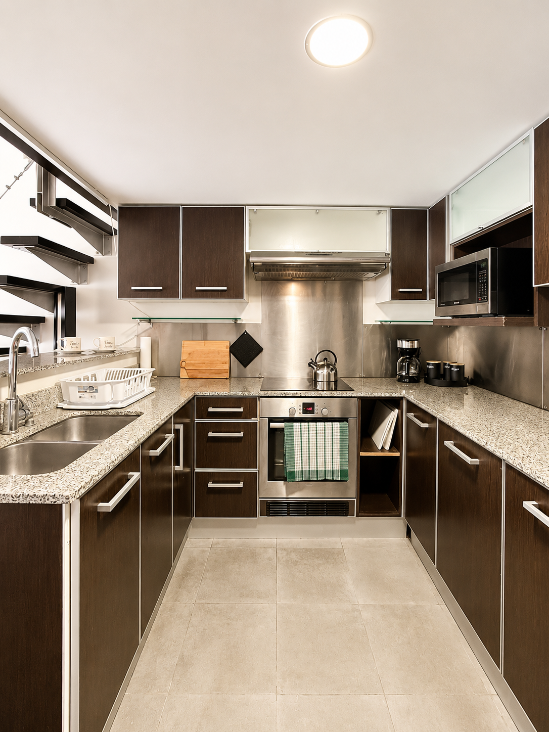 Modern kitchen with dark wood cabinets, granite countertops, stainless steel appliances, and tiled flooring.
