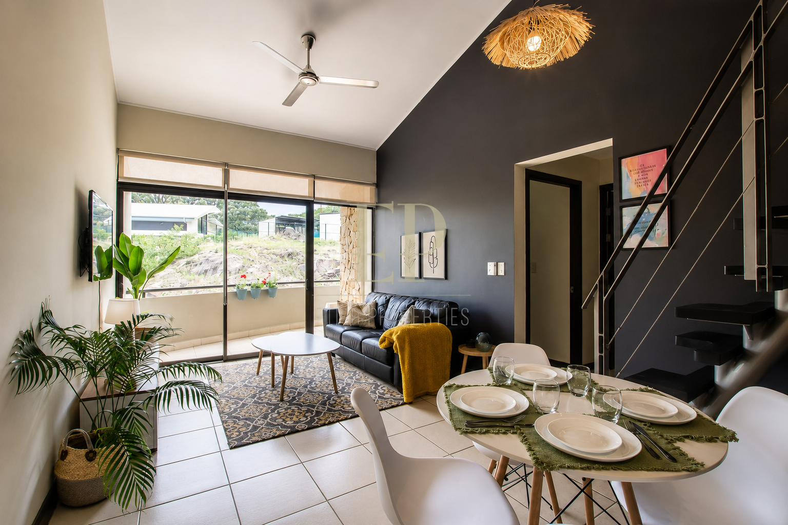 Living room and dining area with a balcony view, black and beige walls, modern decor, plants, ceiling fan, and a dining table set for four.
