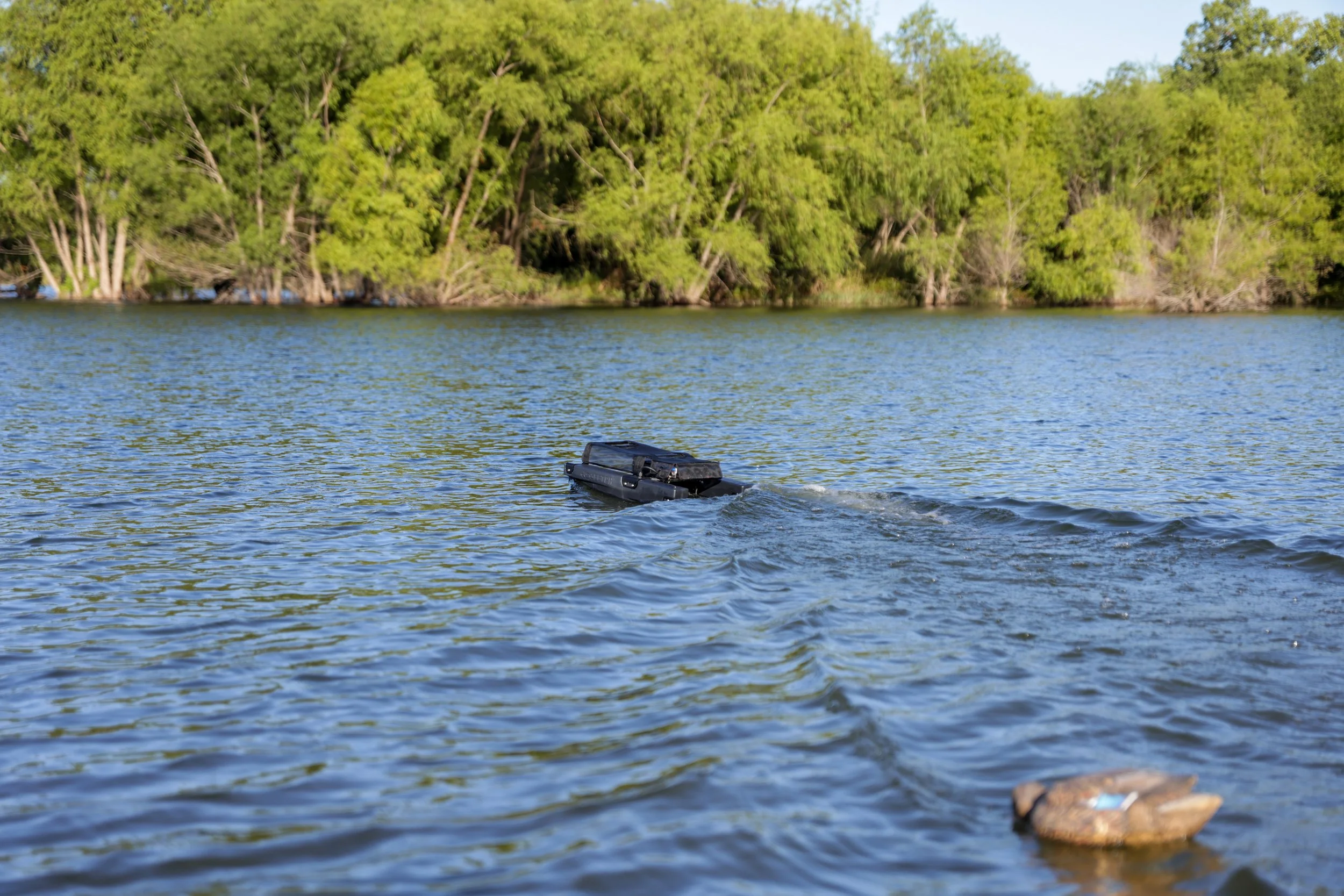 A body of water with green trees along the shoreline and a small boat or kayak partially submerged in the water.