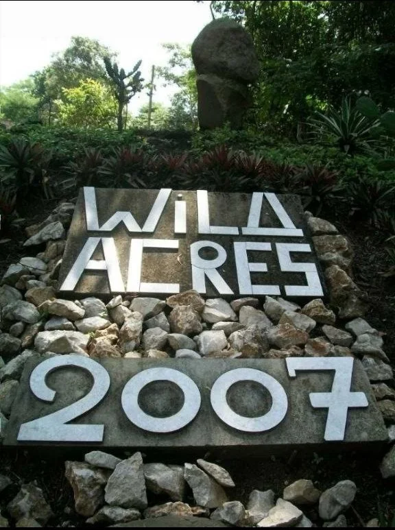 A sign that reads 'Wild Alres' with the year 2007 below it, surrounded by rocks and greenery.