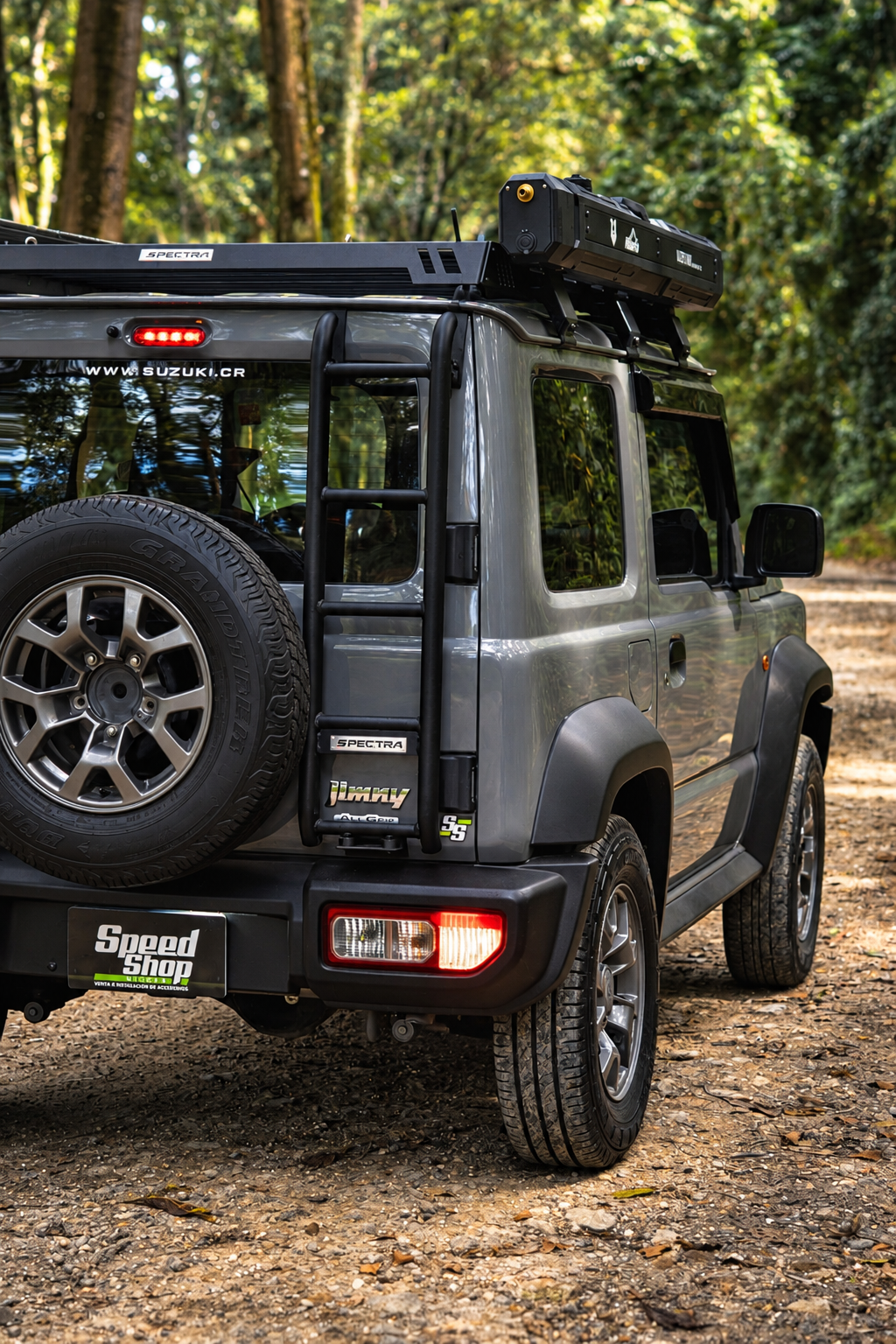 Suzuki Jimny gris equipado con rack de techo Spectra, escalera lateral y accesorio de techo.