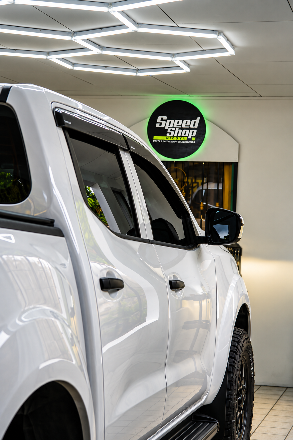 Pickup blanca dentro de SpeedShop Nicoya con el rótulo del negocio al fondo.