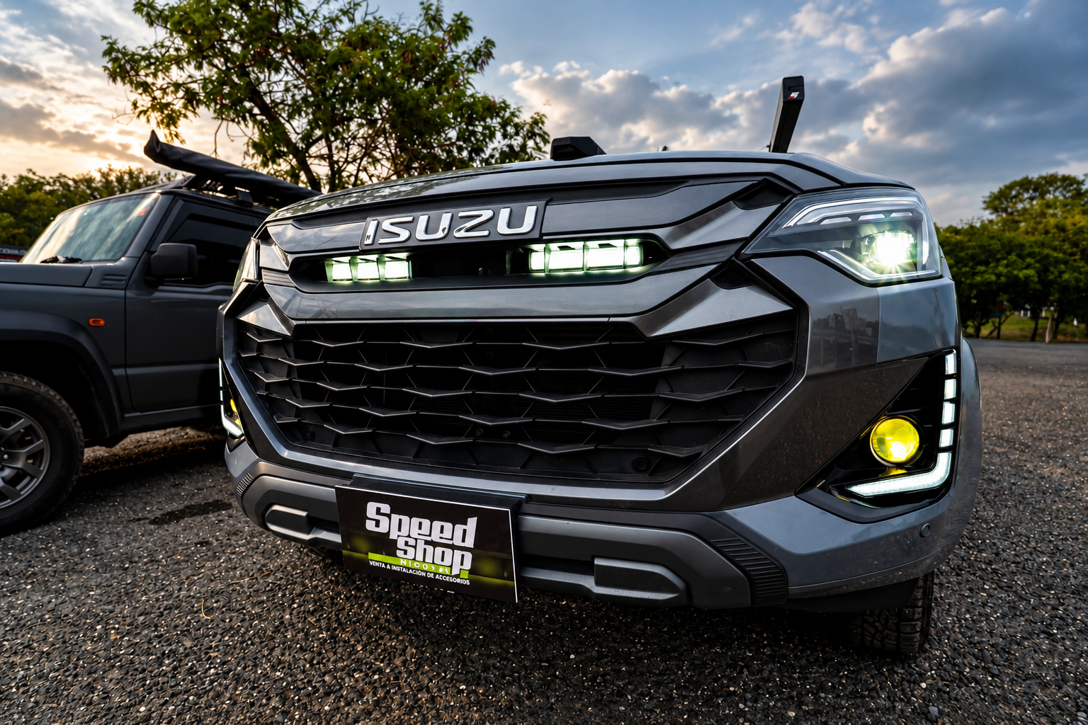 Frente de pickup Isuzu con luces LED, luces de parrilla y halógenos amarillos encendidos.