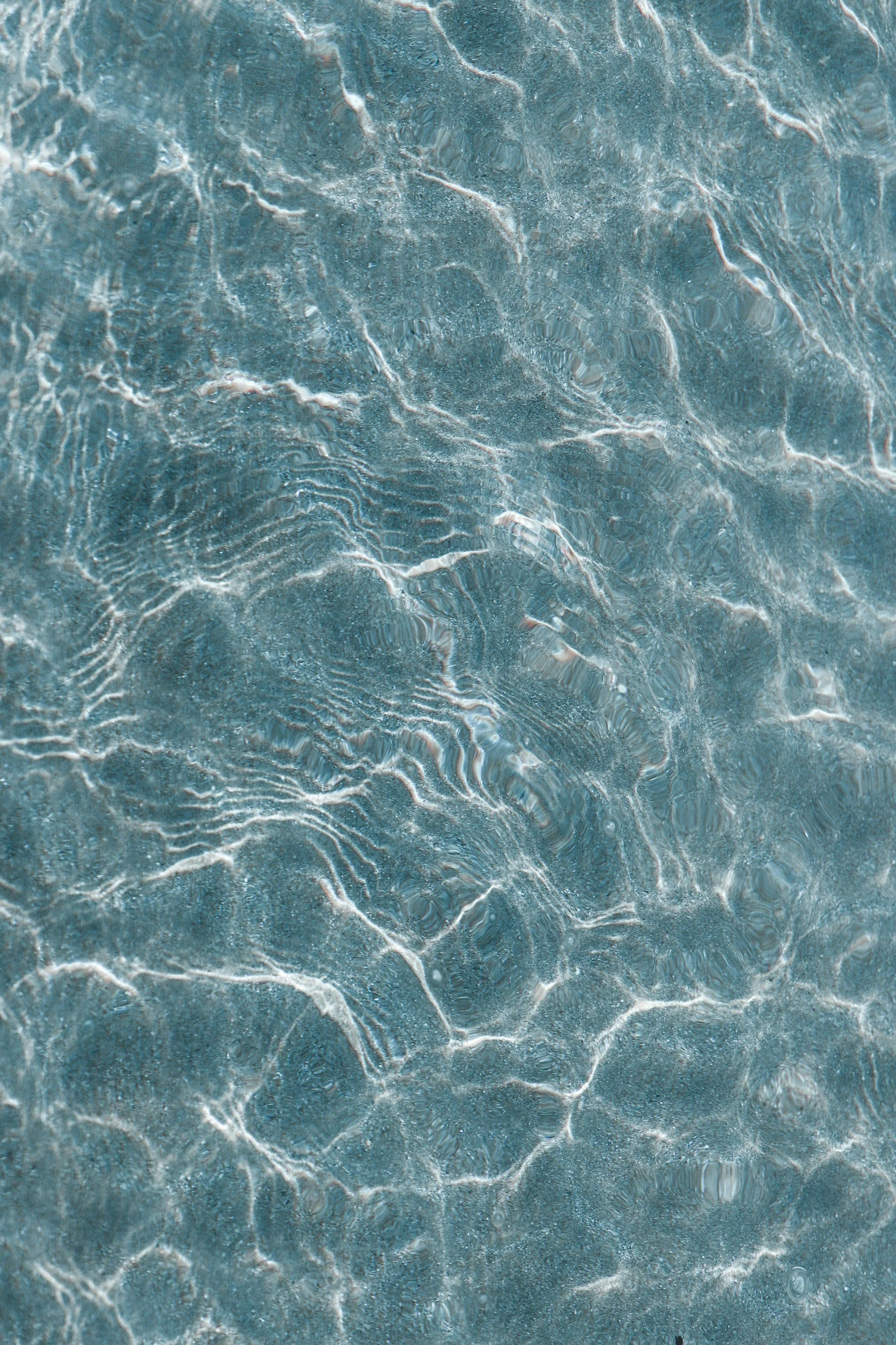 Close-up view of clear, turquoise water with ripples and light reflections on the surface.