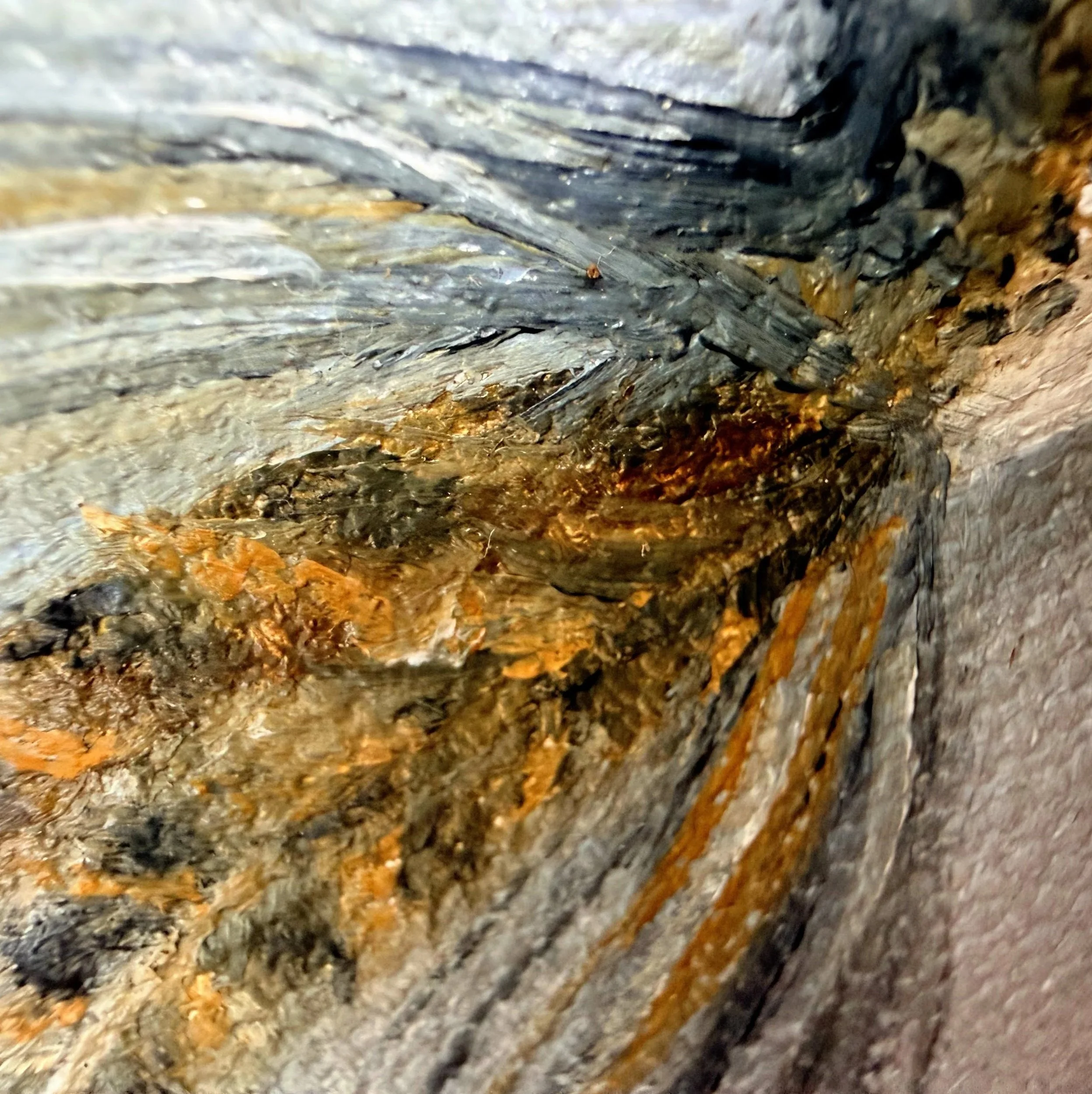 Close-up of a miniature fishing fly painted in oil with delicate feather-like brushwork, mottled brown and gold texture, hook detail, and visible canvas surface.