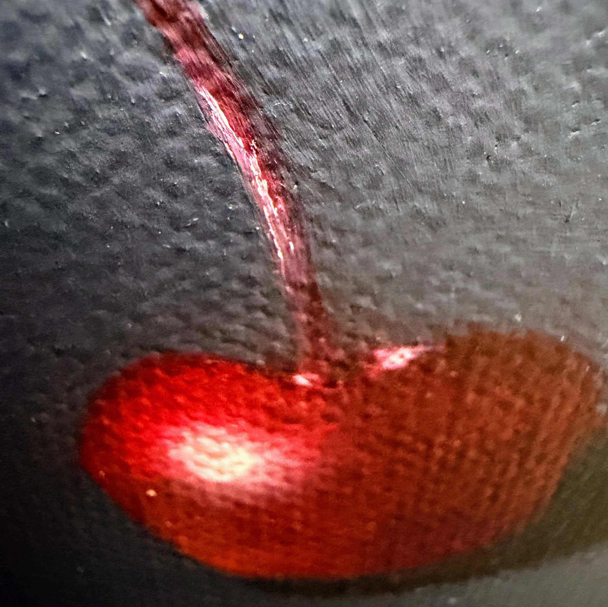 Close-up of a red cherry painted in oil with a glowing highlight, curved stem, soft shadow, and visible canvas texture against a moody dark background.
