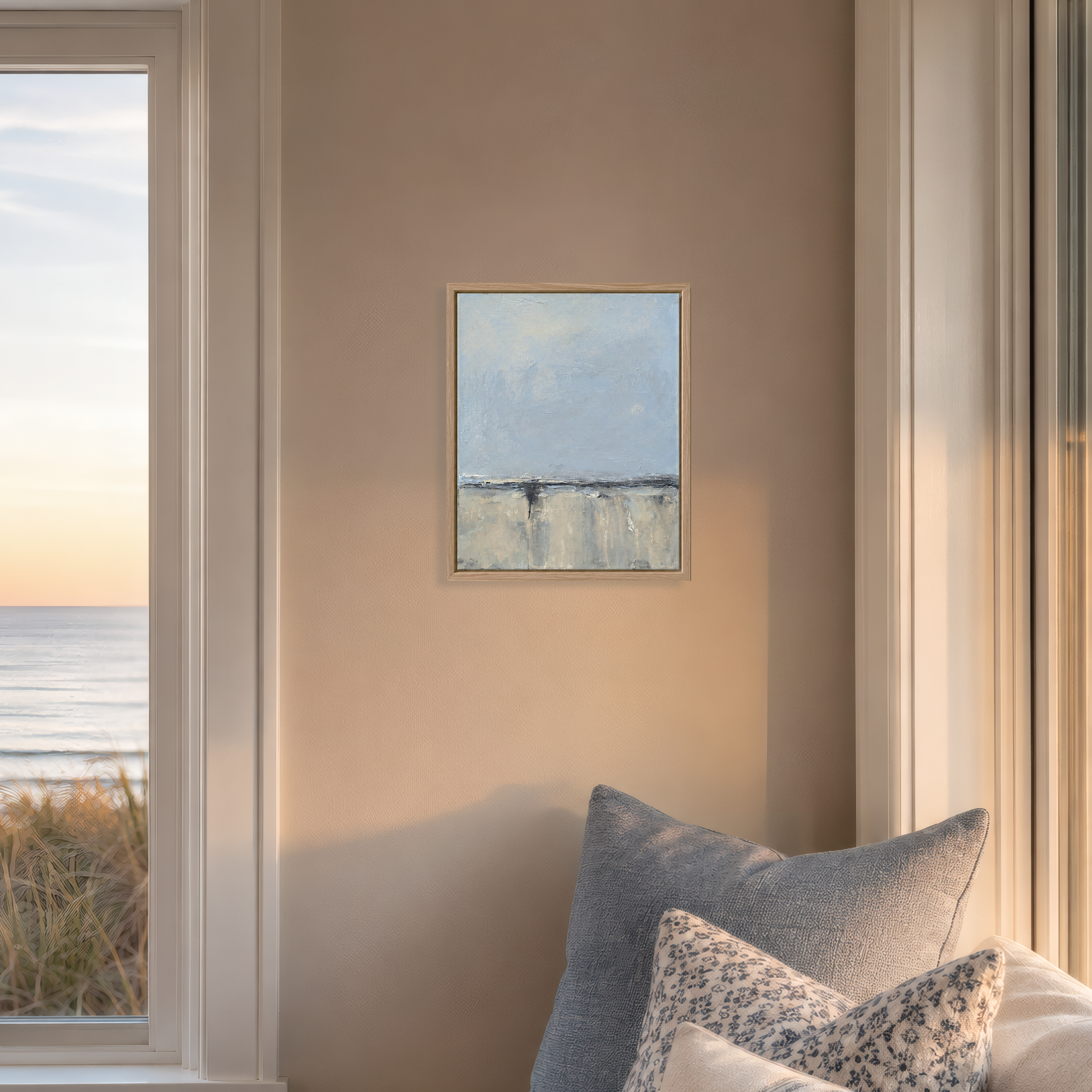 Room mockup: Small coastal abstract landscape painting displayed in a calm modern interior with pale blue, sand, white, and charcoal-gray tones.