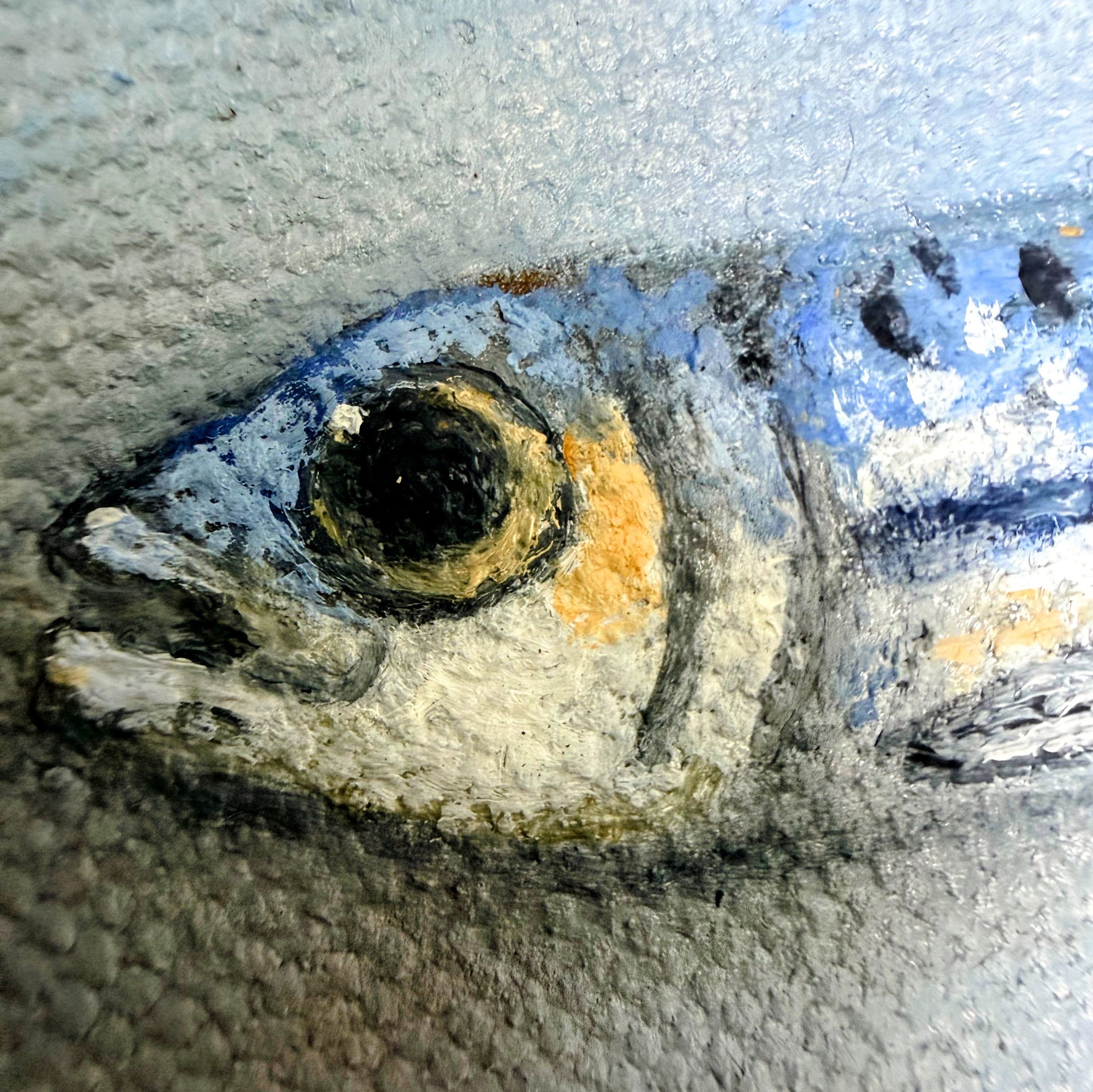 Close-up of a miniature anchovy painted in oil with reflective blue-silver highlights, a dark eye, small speckles, and visible canvas texture.