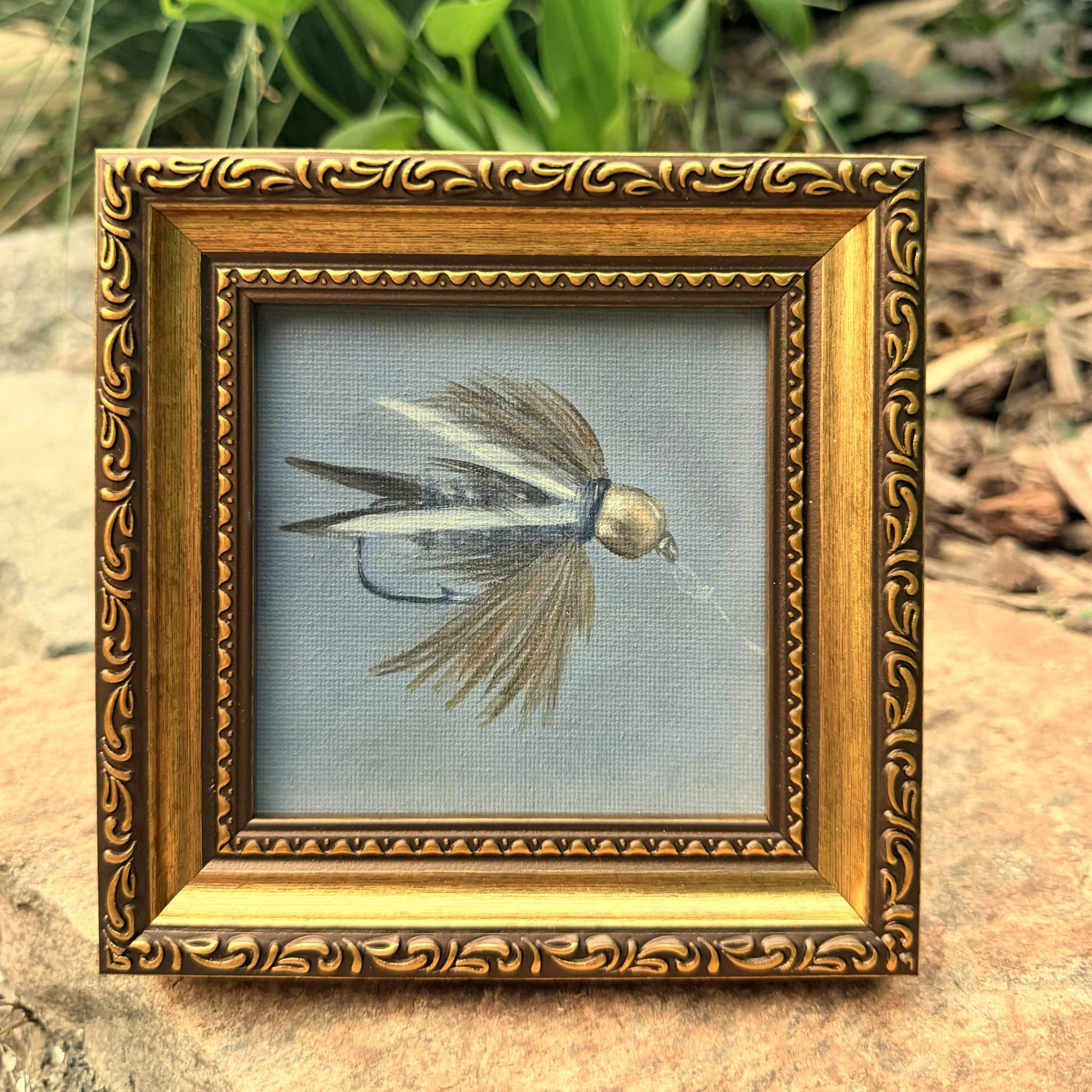 Small square silver minnow fishing fly oil painting shown on canvas board, ready to frame or display as part of a collected wall.
