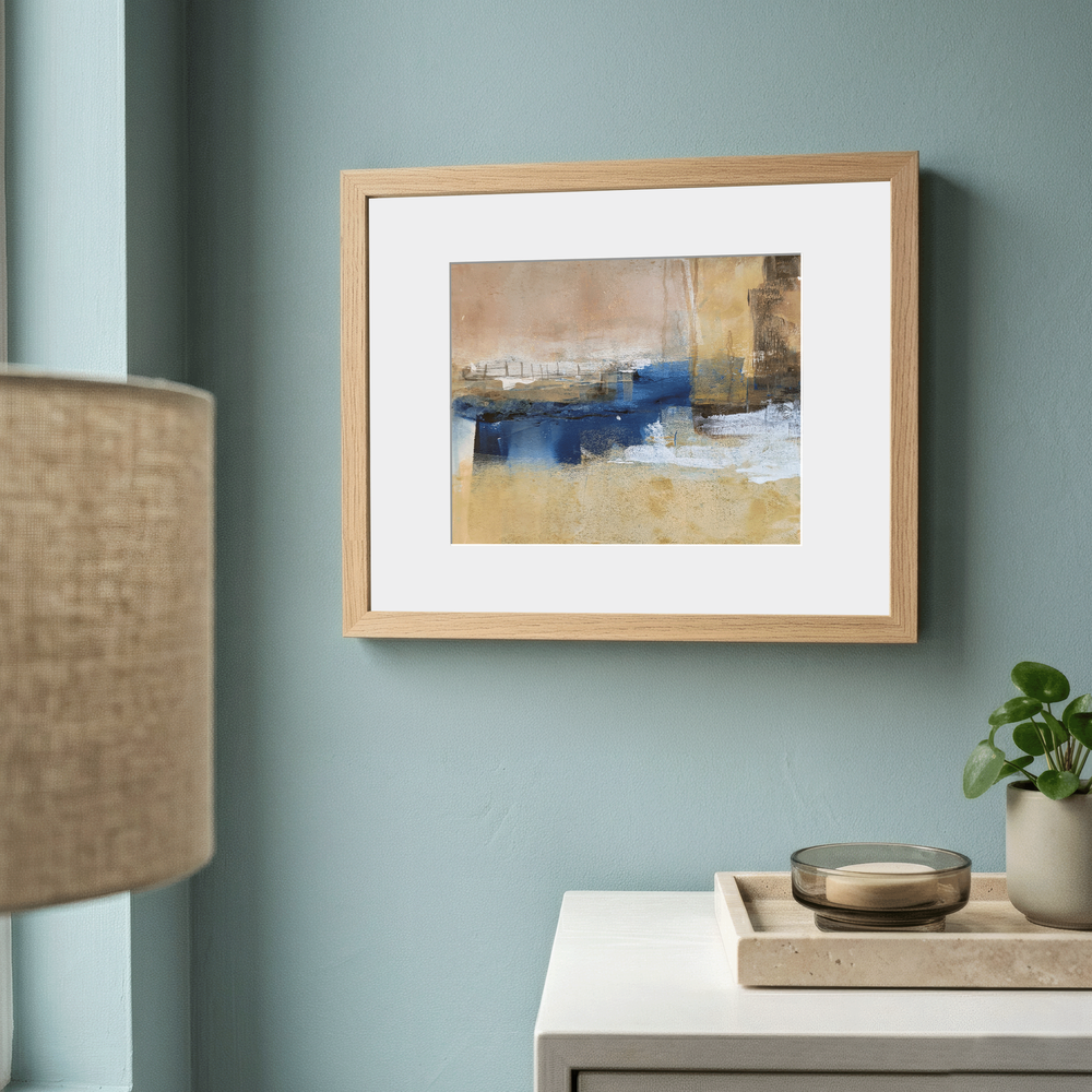 Small abstract painting in a light wood frame on a blue-green wall above a white cabinet, showing original art placed in a quiet interior corner.