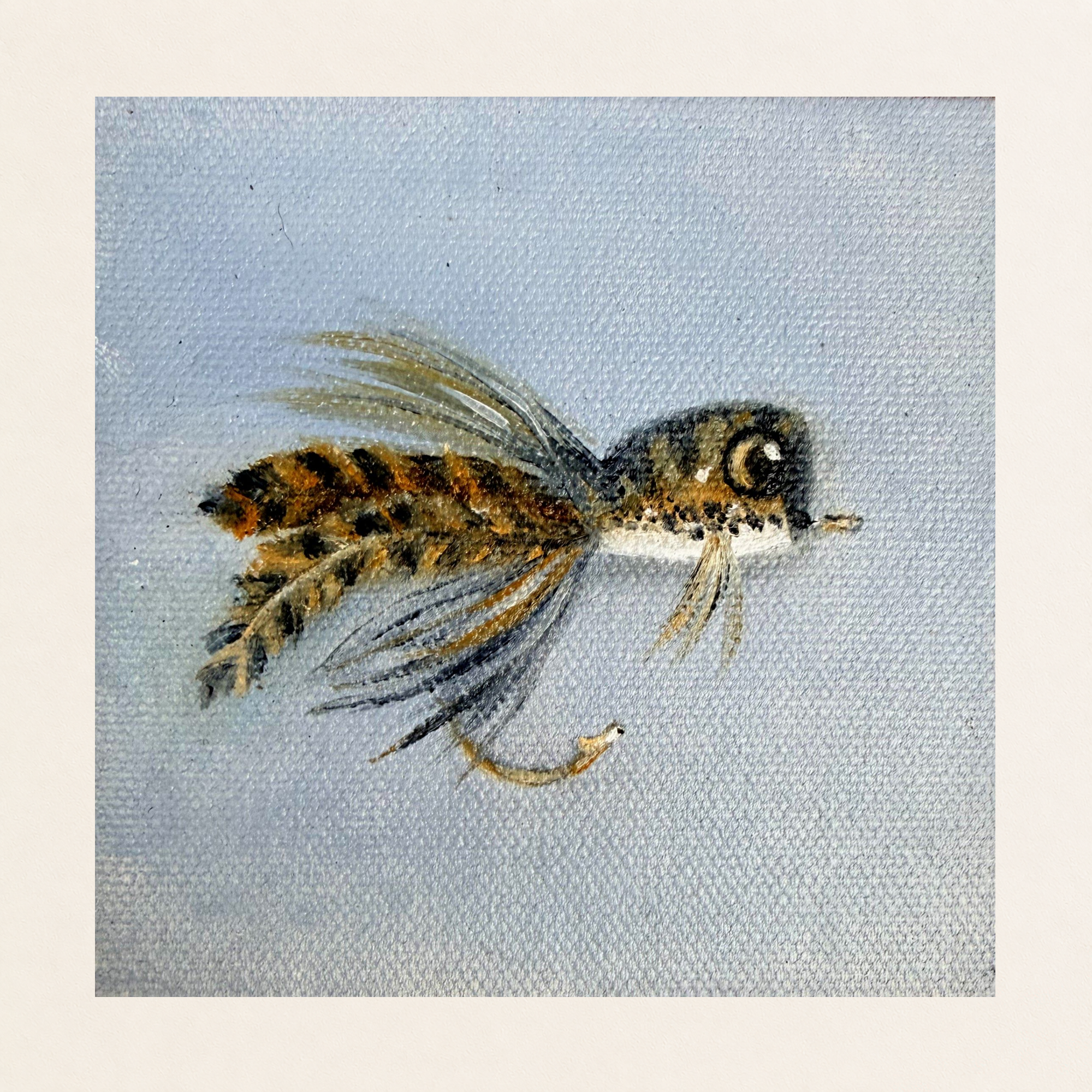 Original 4 x 4 inch oil painting of a frog-inspired fishing fly lure with feathered details, dark markings, and warm gold accents against a pale blue textured background on canvas board.