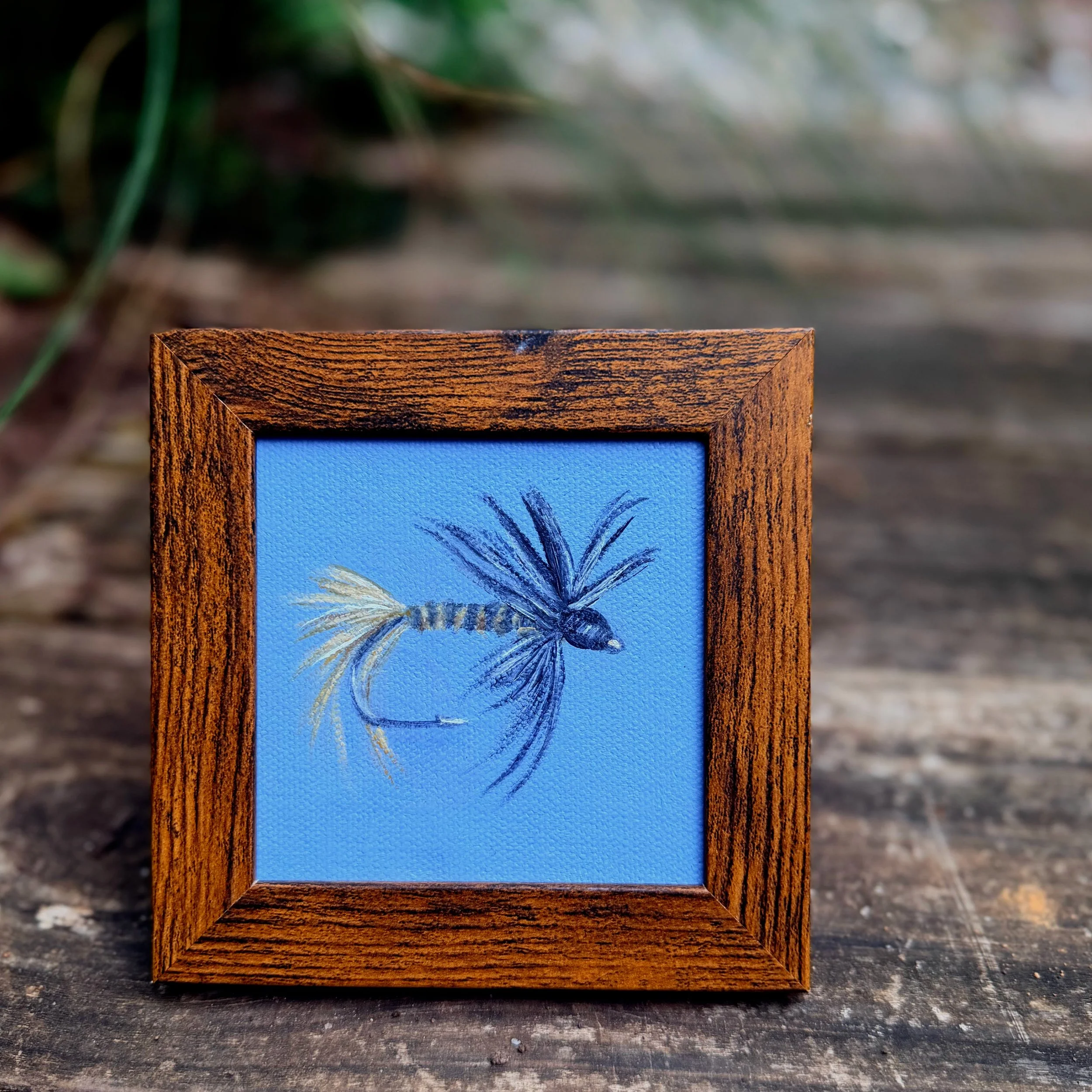 Small square black gnat fishing fly oil painting shown on canvas board, ready to frame or display as part of a collected wall.