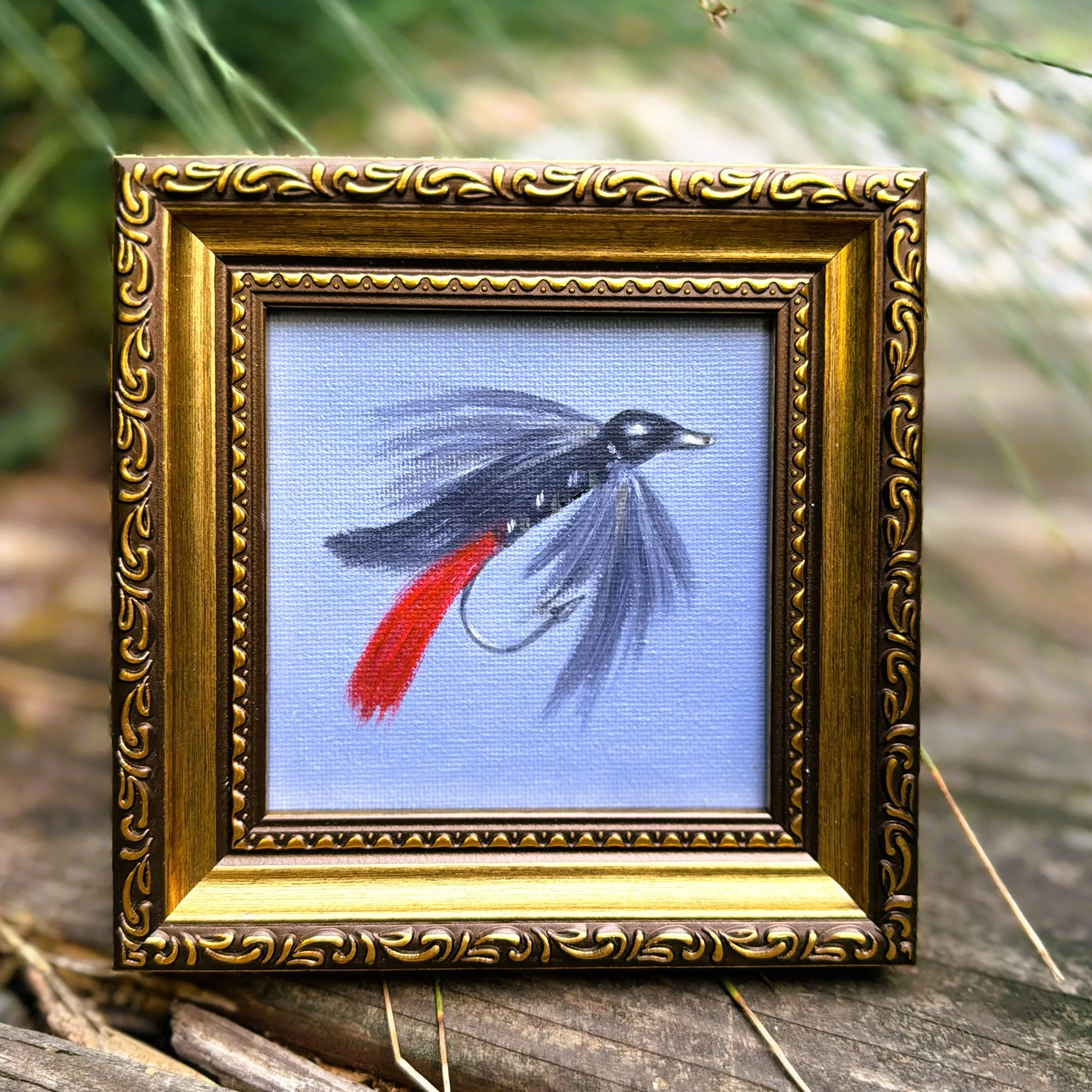 Small square red tail fishing fly oil painting shown on canvas board, ready to frame or display as part of a collected wall.