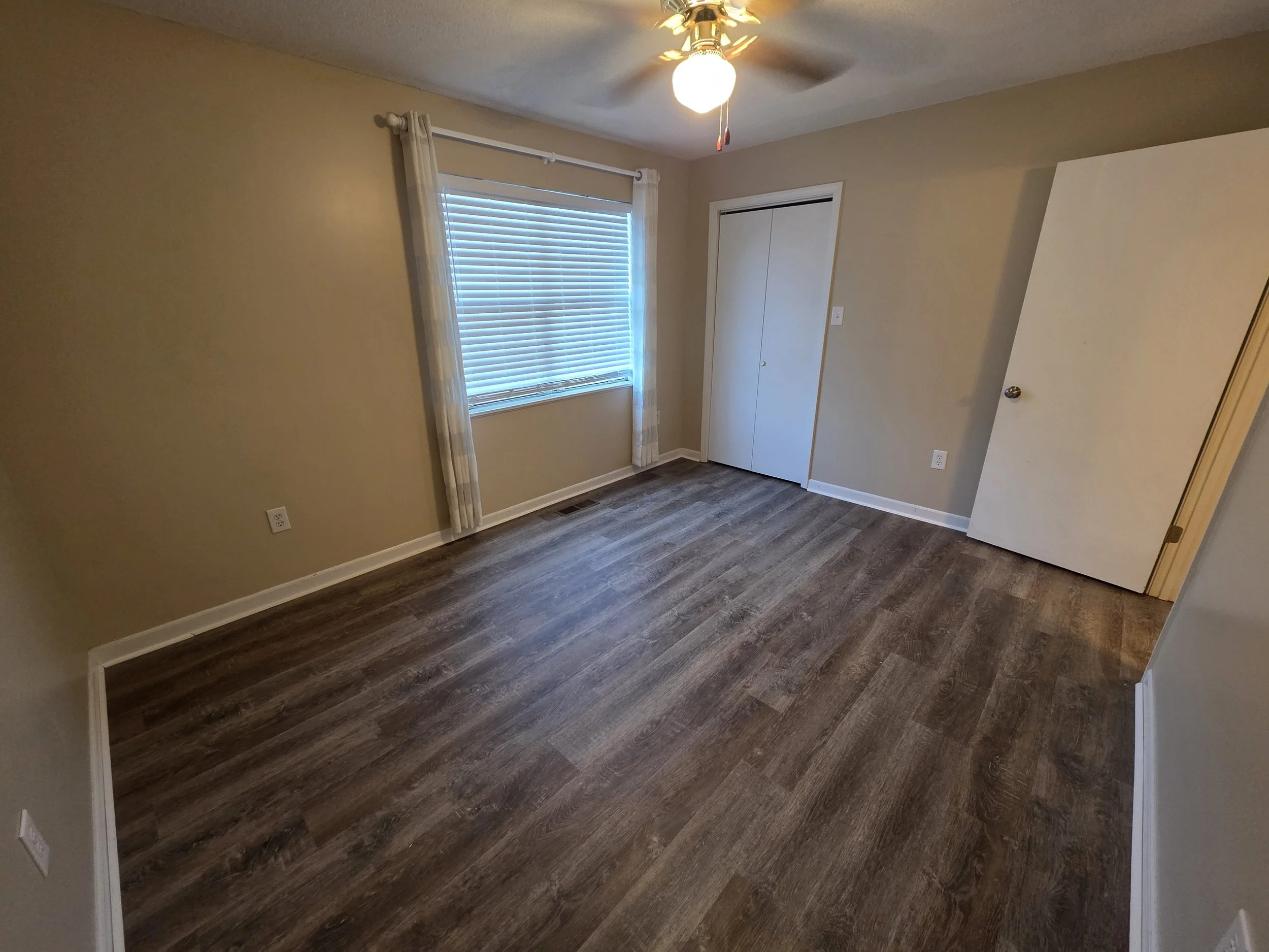 Upstairs bedroom with new LVP flooring, window, and closet in a 2-bedroom Greenwood townhouse