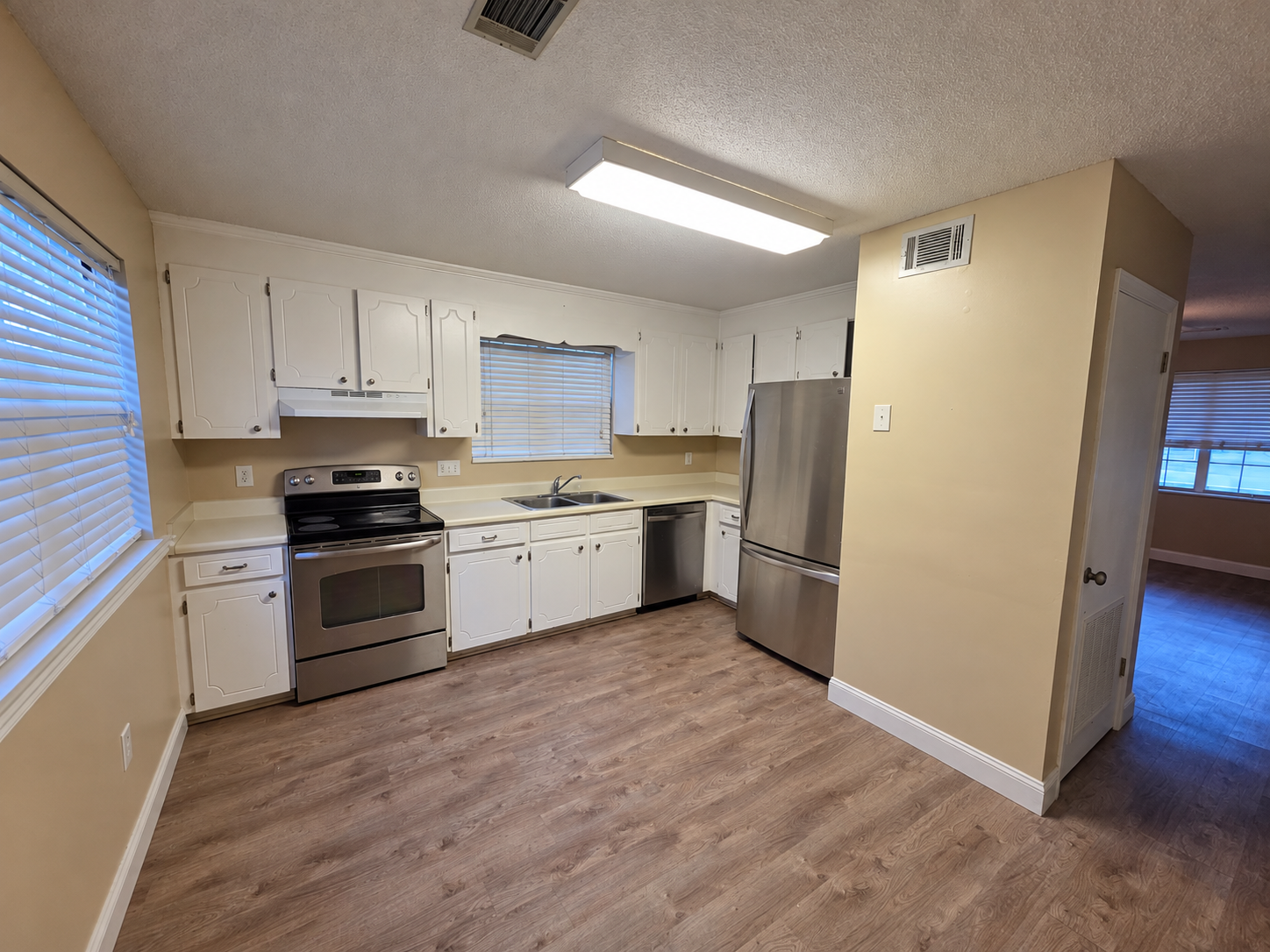 Kitchen with white cabinets, stainless steel appliances, and LVP flooring in a Greenwood townhouse rental