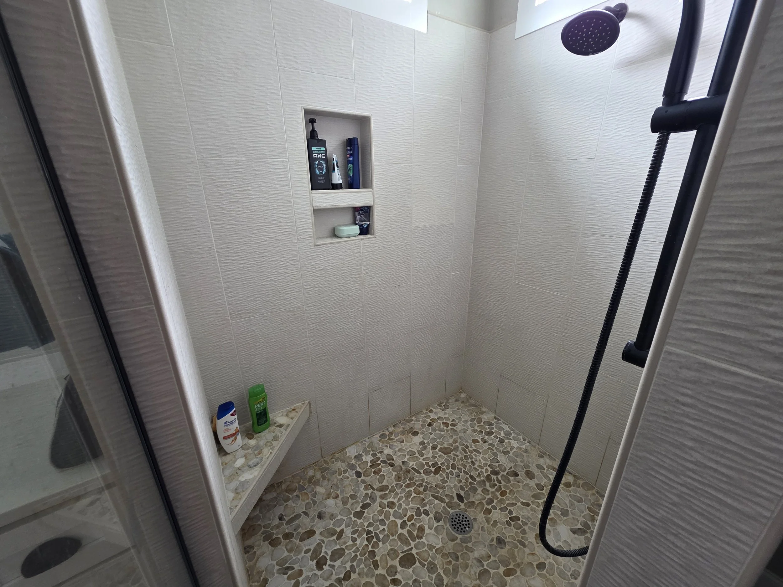 Walk-in tile shower with pebble floor in Greenwood SC rental home.