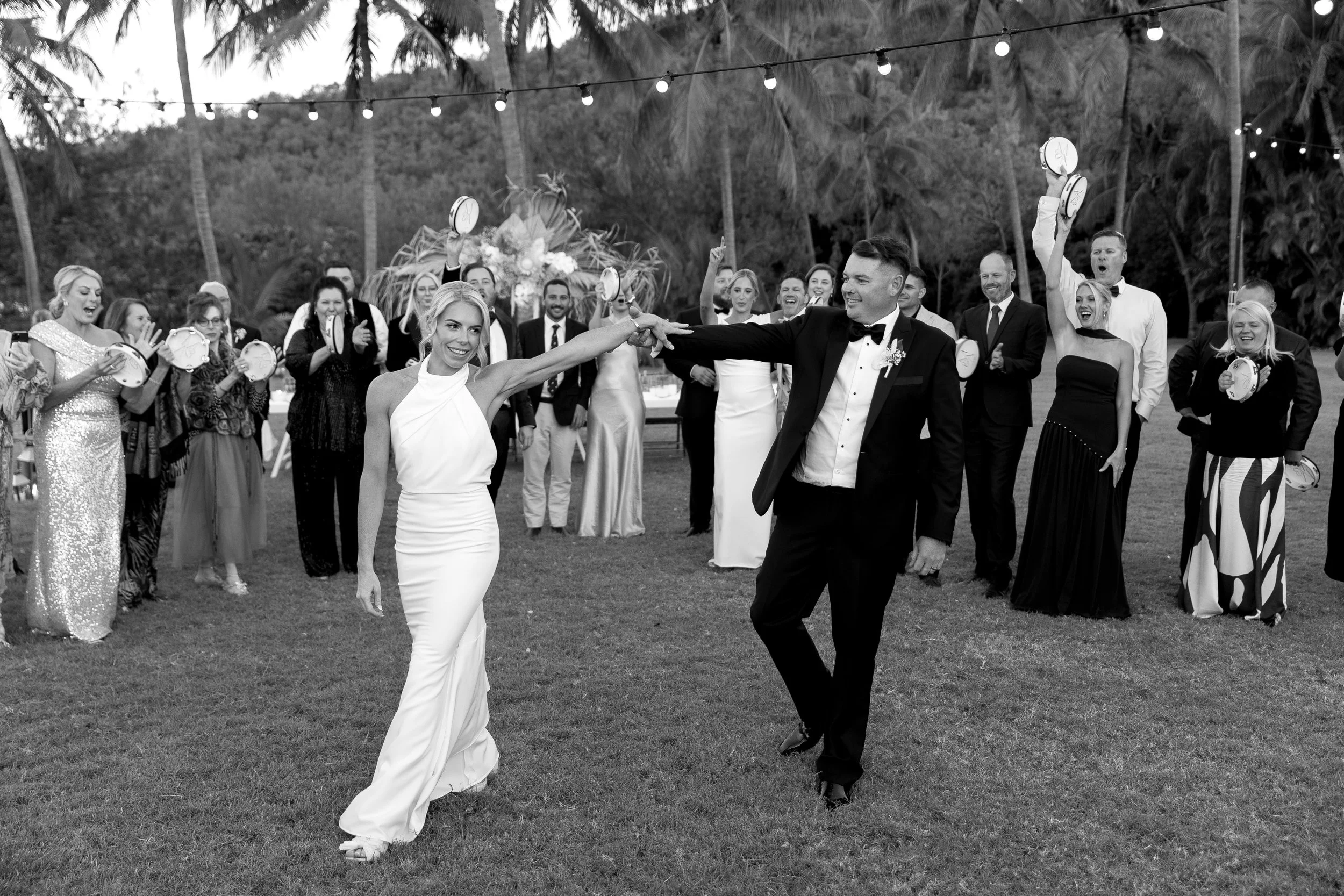 Bride and groom celebrating their luxury Whitsunday wedding reception surrounded by guests, featuring coastal wedding styling, elegant event design and romantic celebrations by Salt & Silk Collective in Airlie Beach.